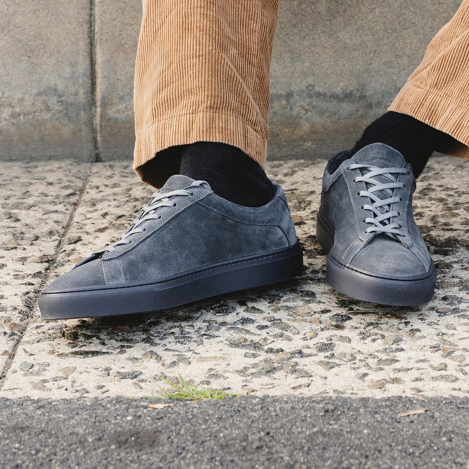 a pair of gray suede sneakers on a man's feet