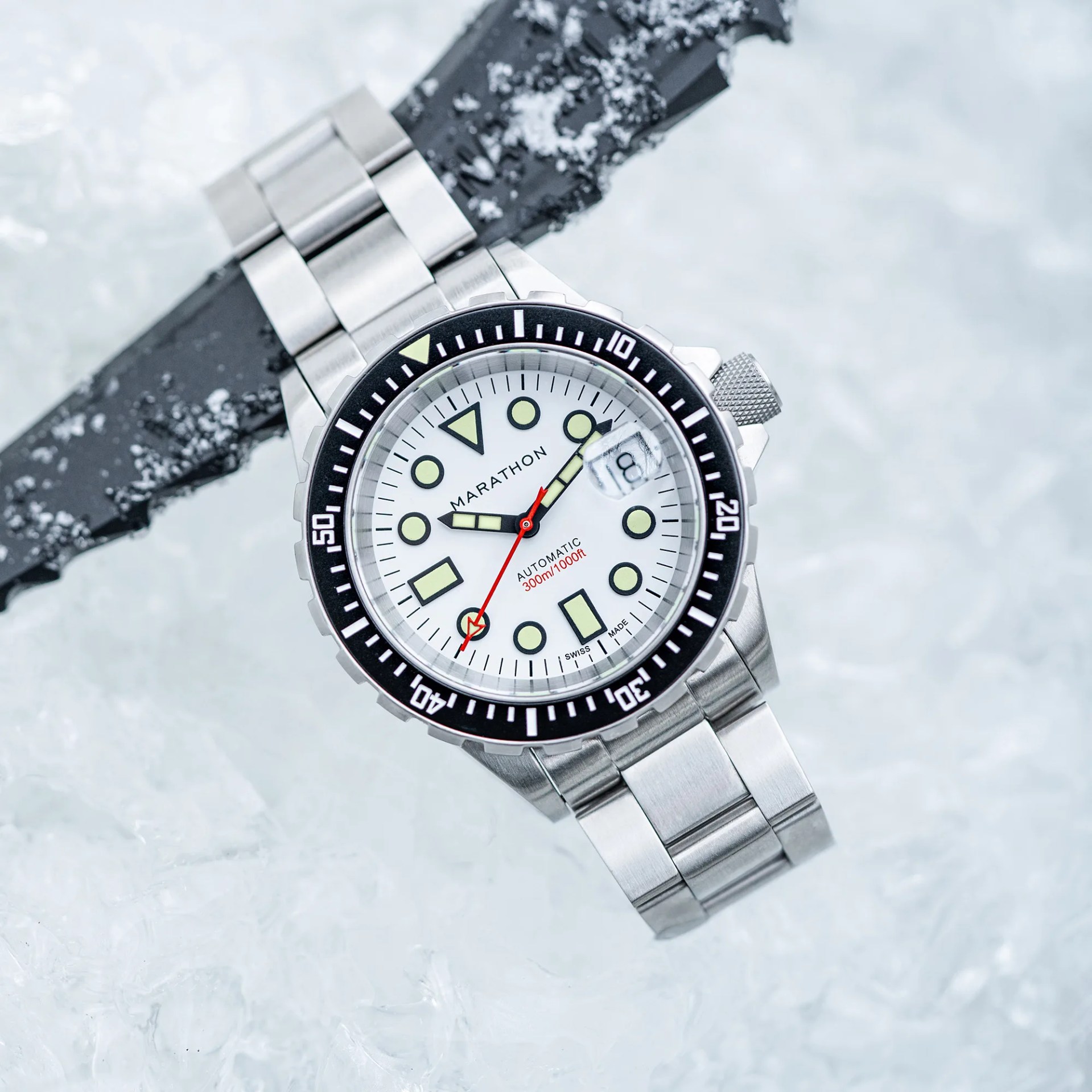 a steel dive watch with a white dial sitting in ice