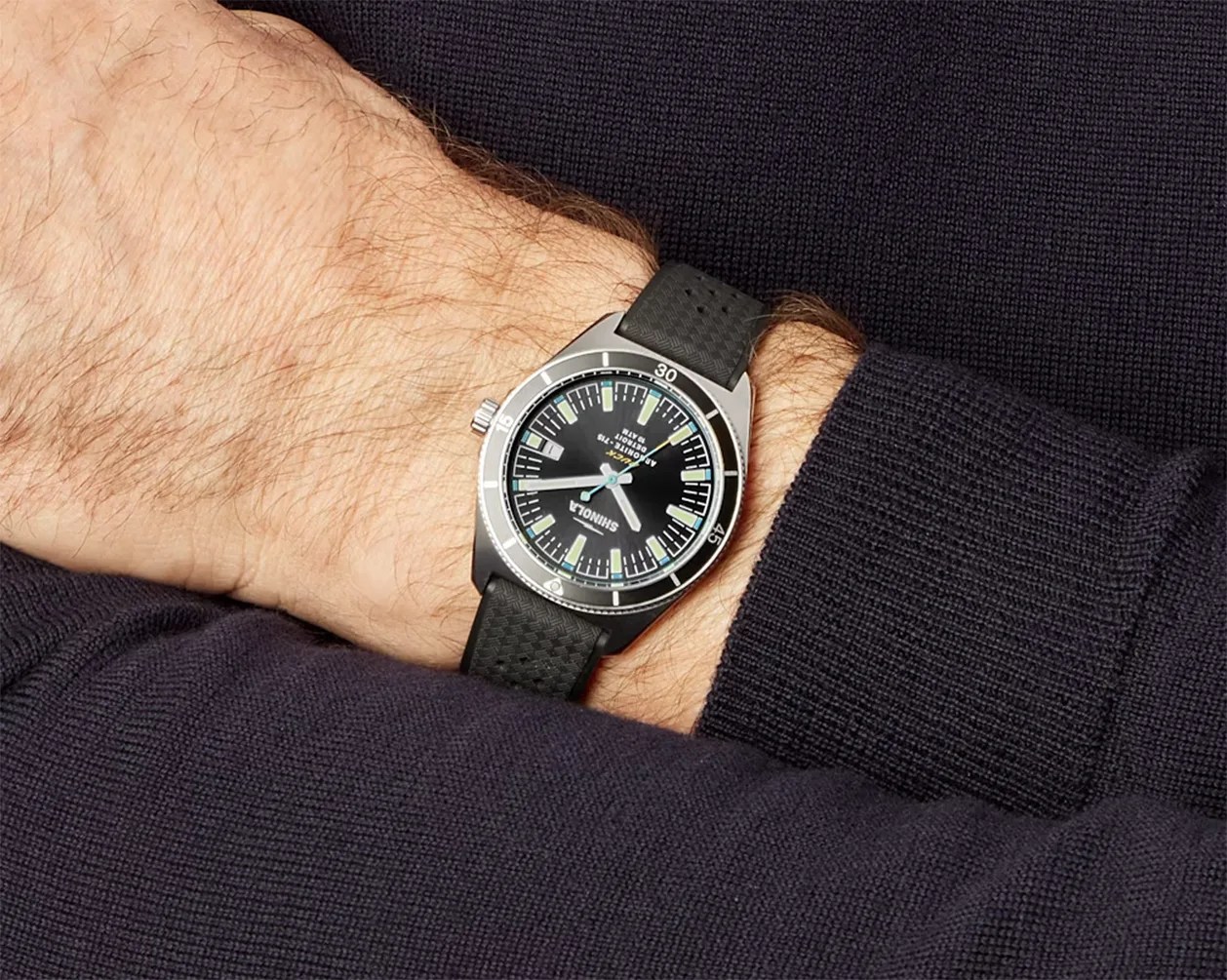 a black dive watch on a man's wrist