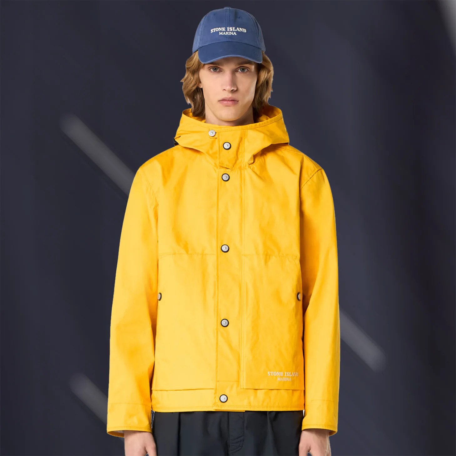 a man wearing a yellow Stone Island raincoat