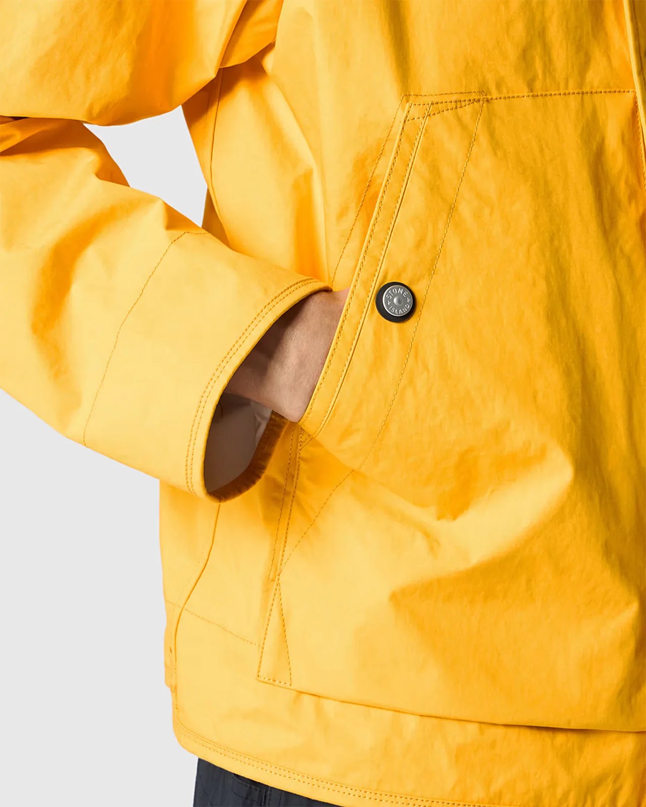 a man with his hand in the pocket of a yellow raincoat