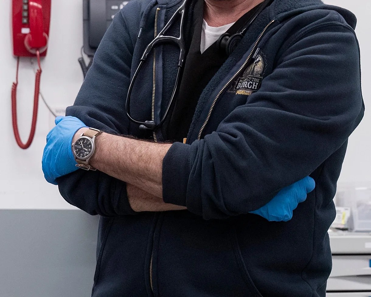 a doctor in a blue hoodie wearing a seiko watch