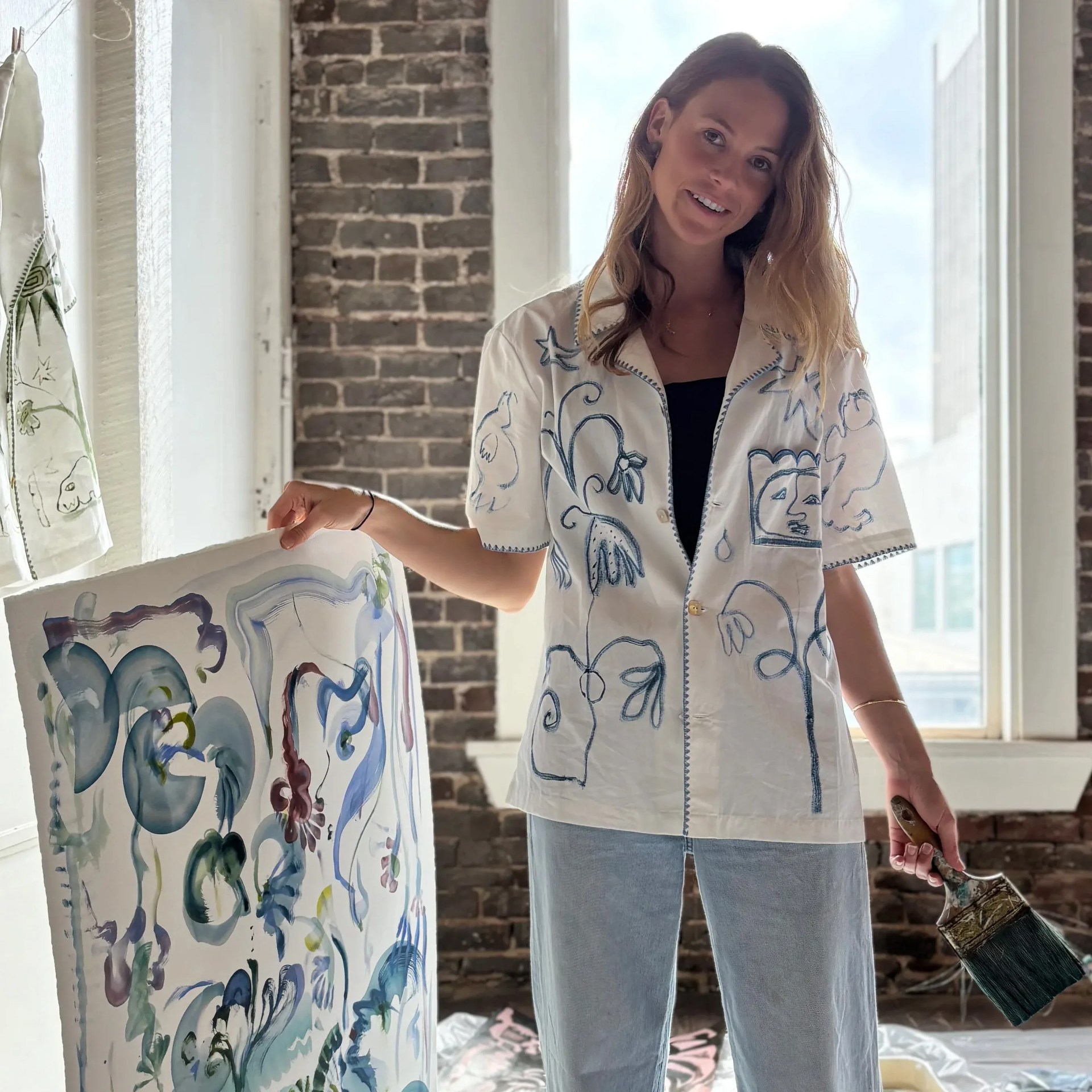 a woman in a white short sleeve shirt holding a painting
