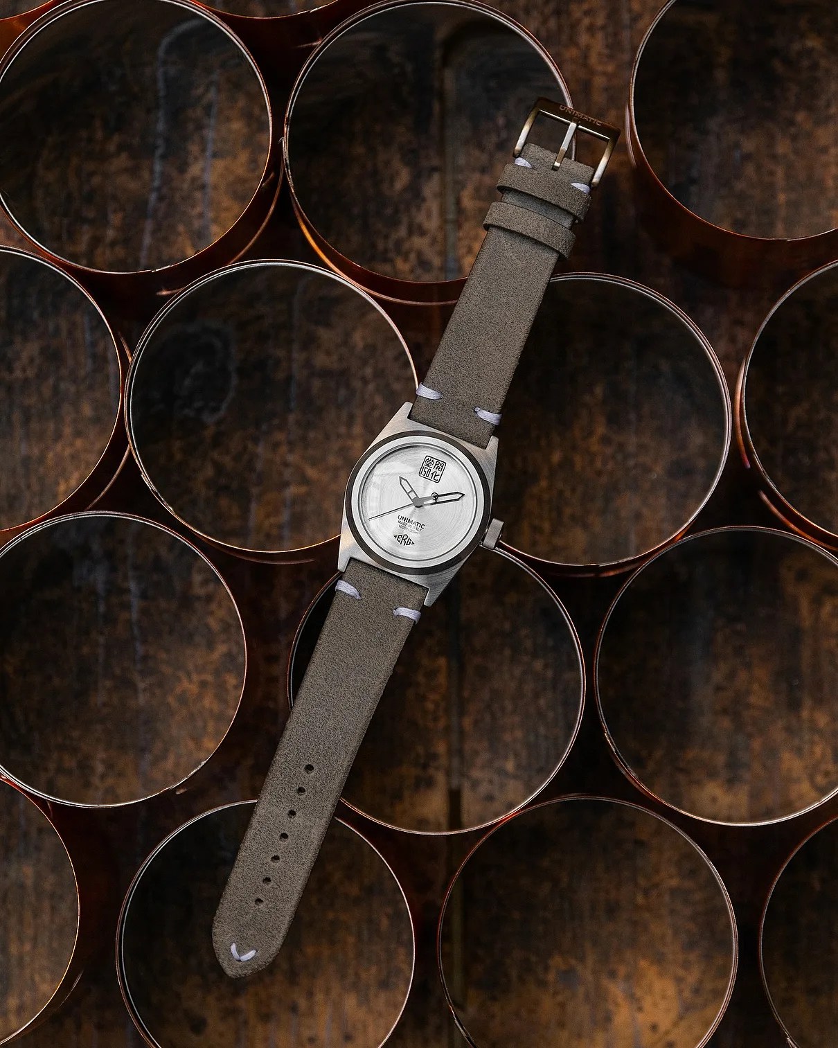 a silver dial watch with a gray leather strap