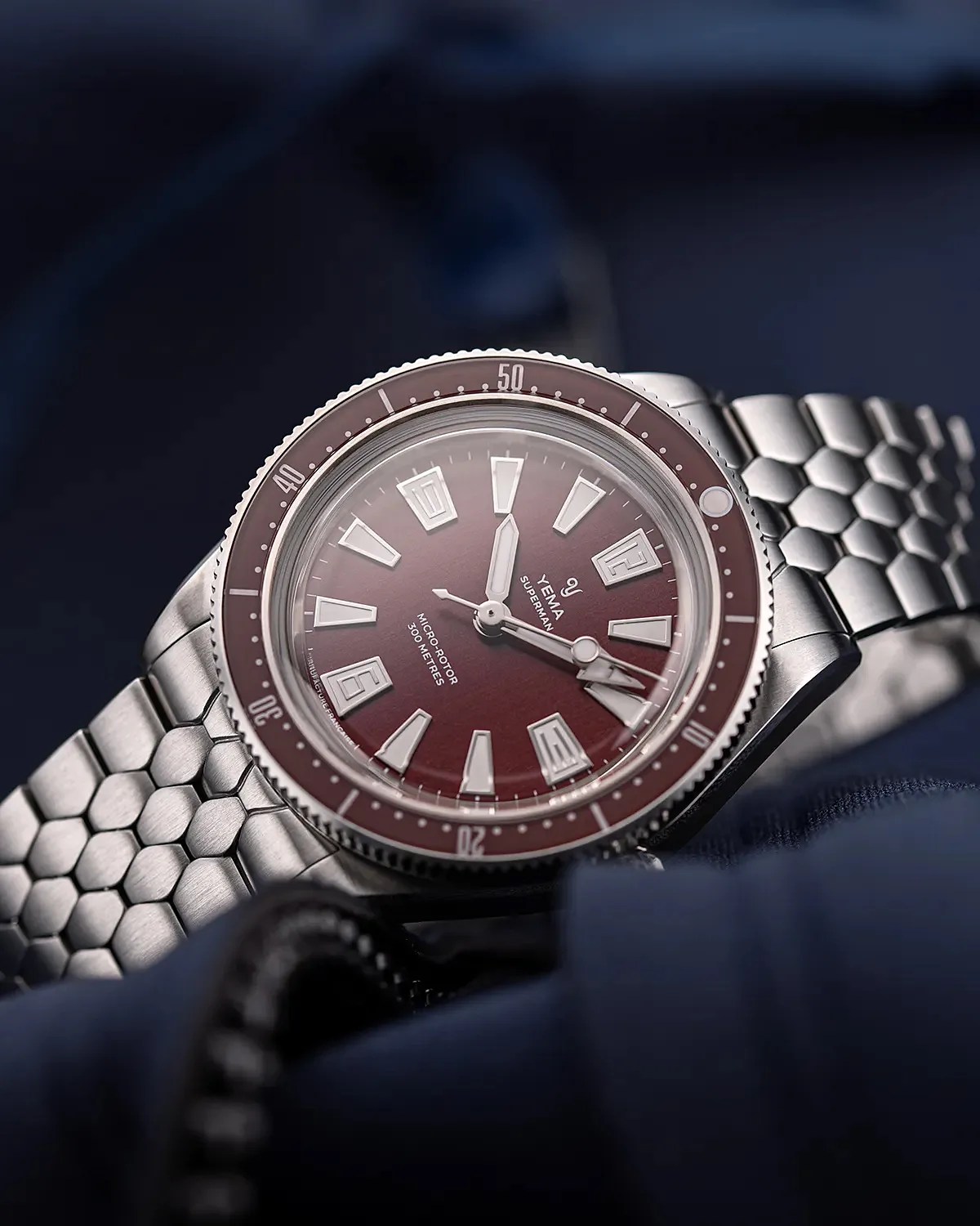 a steel Yema dive watch with a red dial