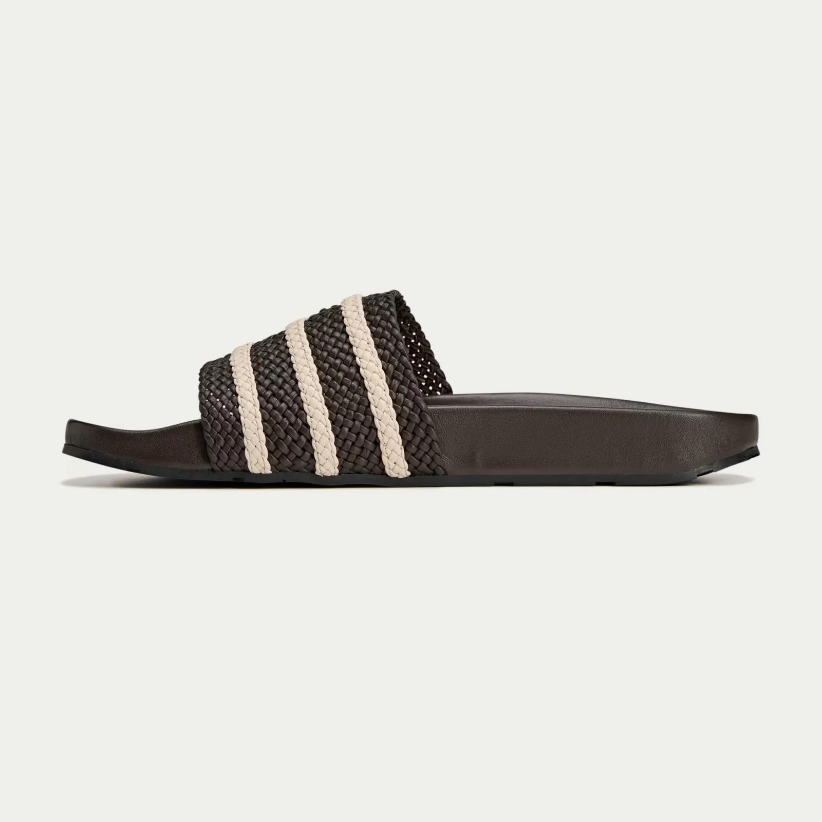 A Wales Bonner Adidas Adilette slides in brown, shown in profile, with the toe facing the left-hand side of the image. 