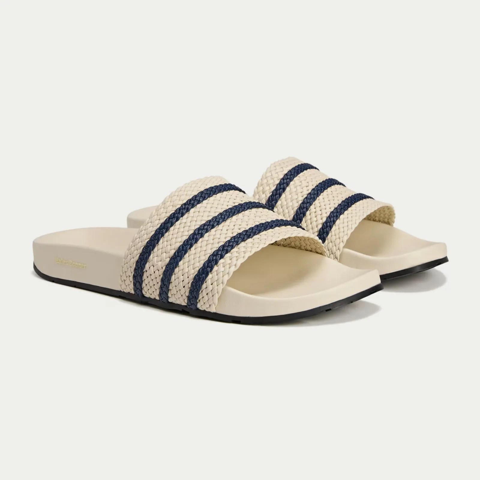 A pair of Wales Bonner Adidas Adilette slides sandals in white shown pointing at an angle to the right-hand edge of the screen.