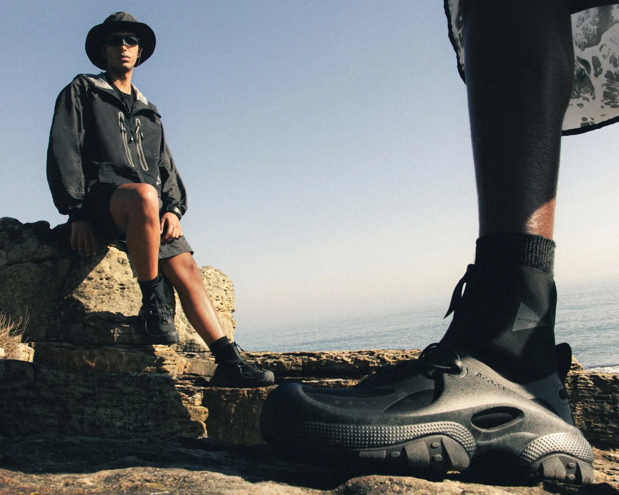 Two people wearing End x and Wander x Crocs Trailbreak sneakers on beach
