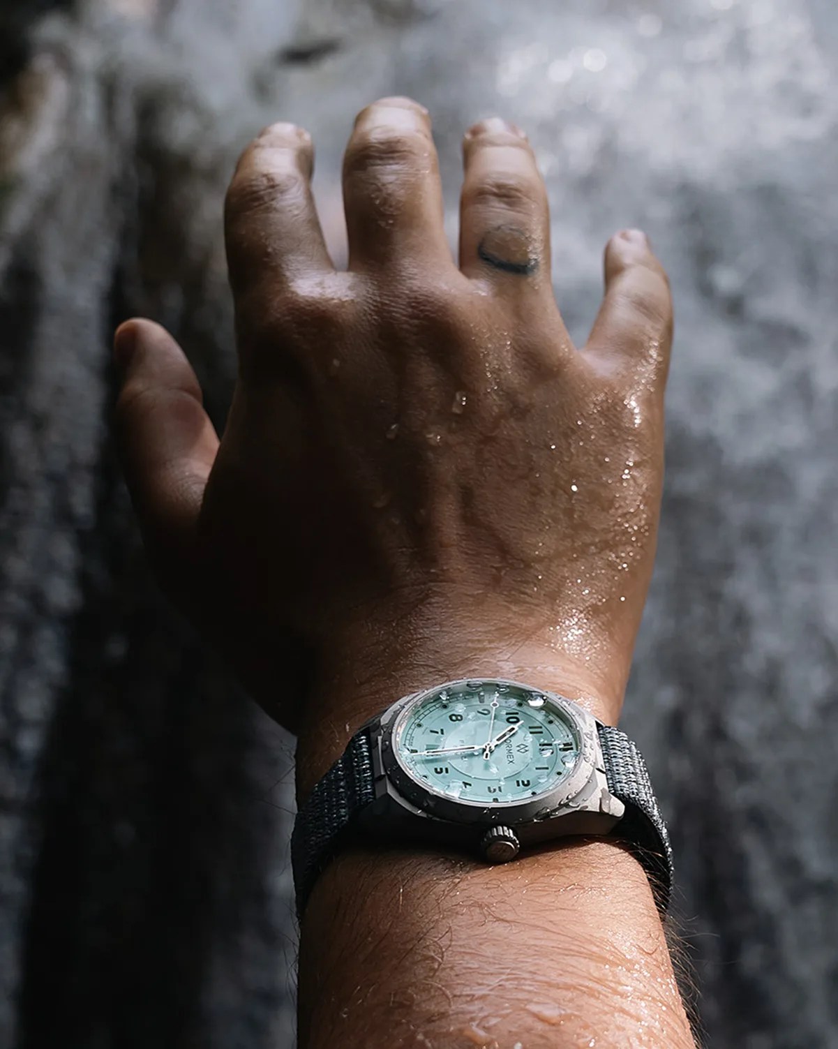 a blue field watch on a man's wrist