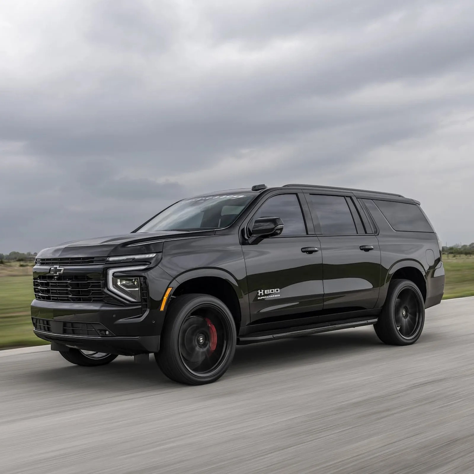 An angled view of the 2025 Chevy Suburban H 600 Hennessey Performance driving on a track towards the left hand side of the iamge