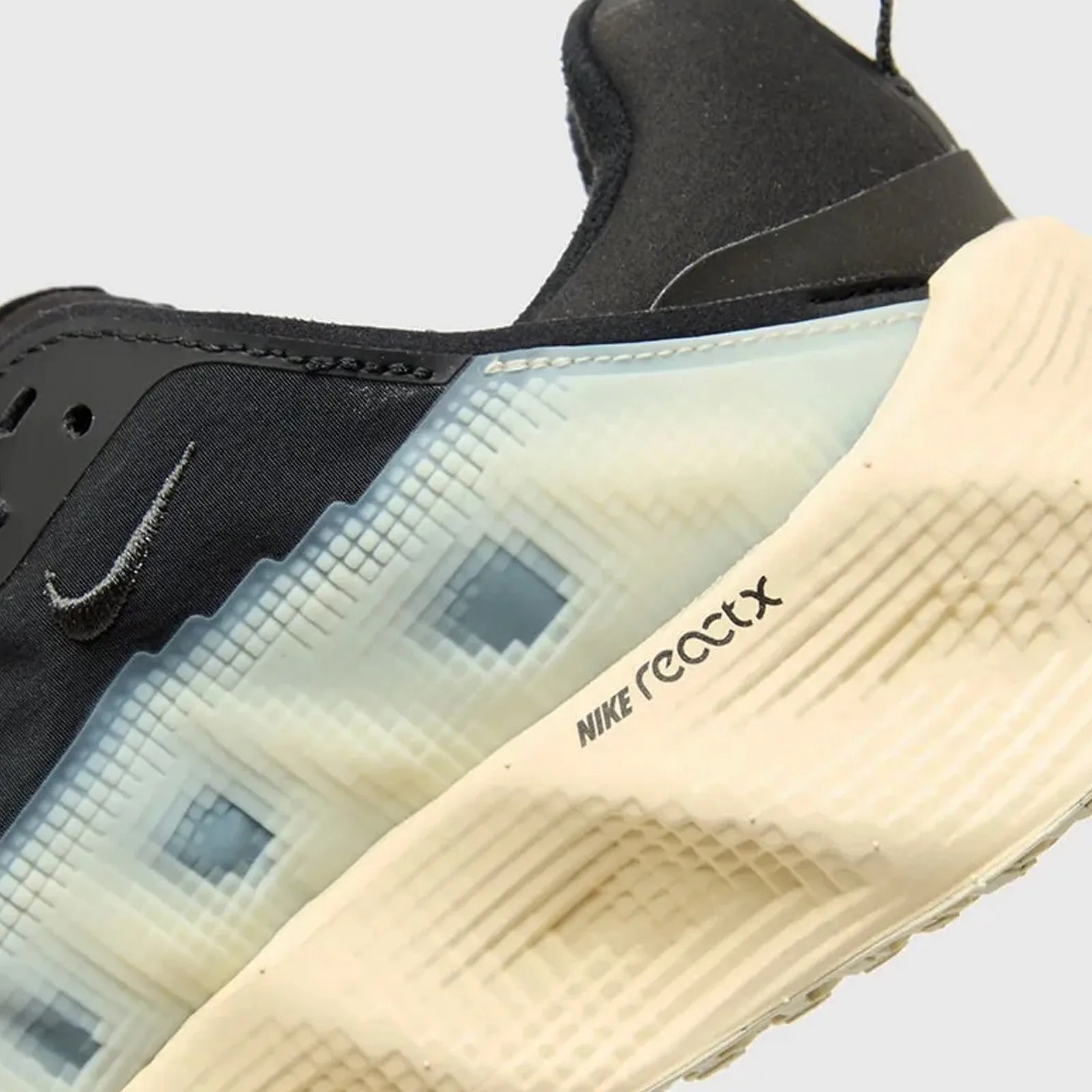 A close-up of the heel and mudguard of the Nike AVA Rover sneaker in black and creamy white highlights the sneakers' pixel pattern.
