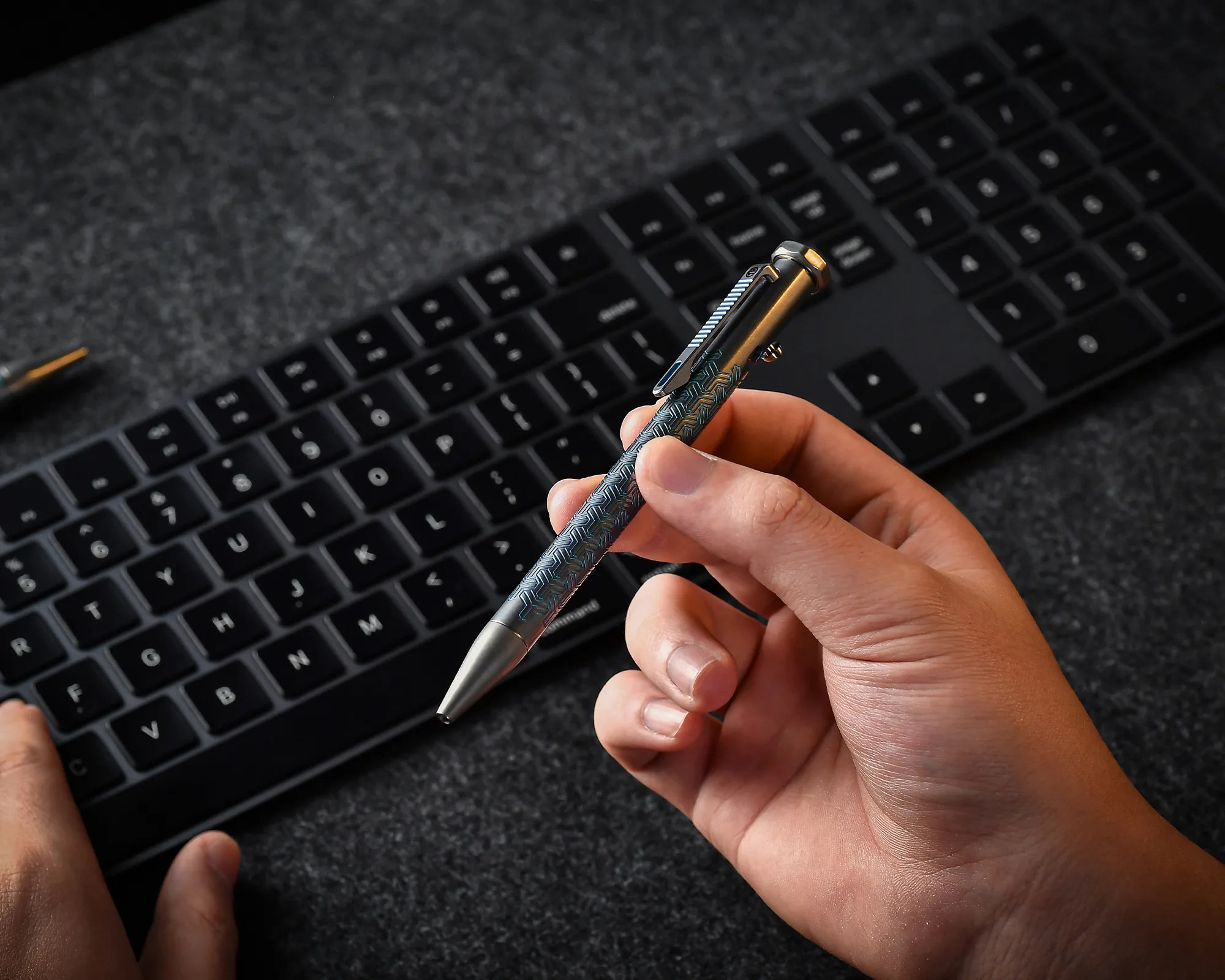 Tacray Spinium EDC Pen in hand above keyboard