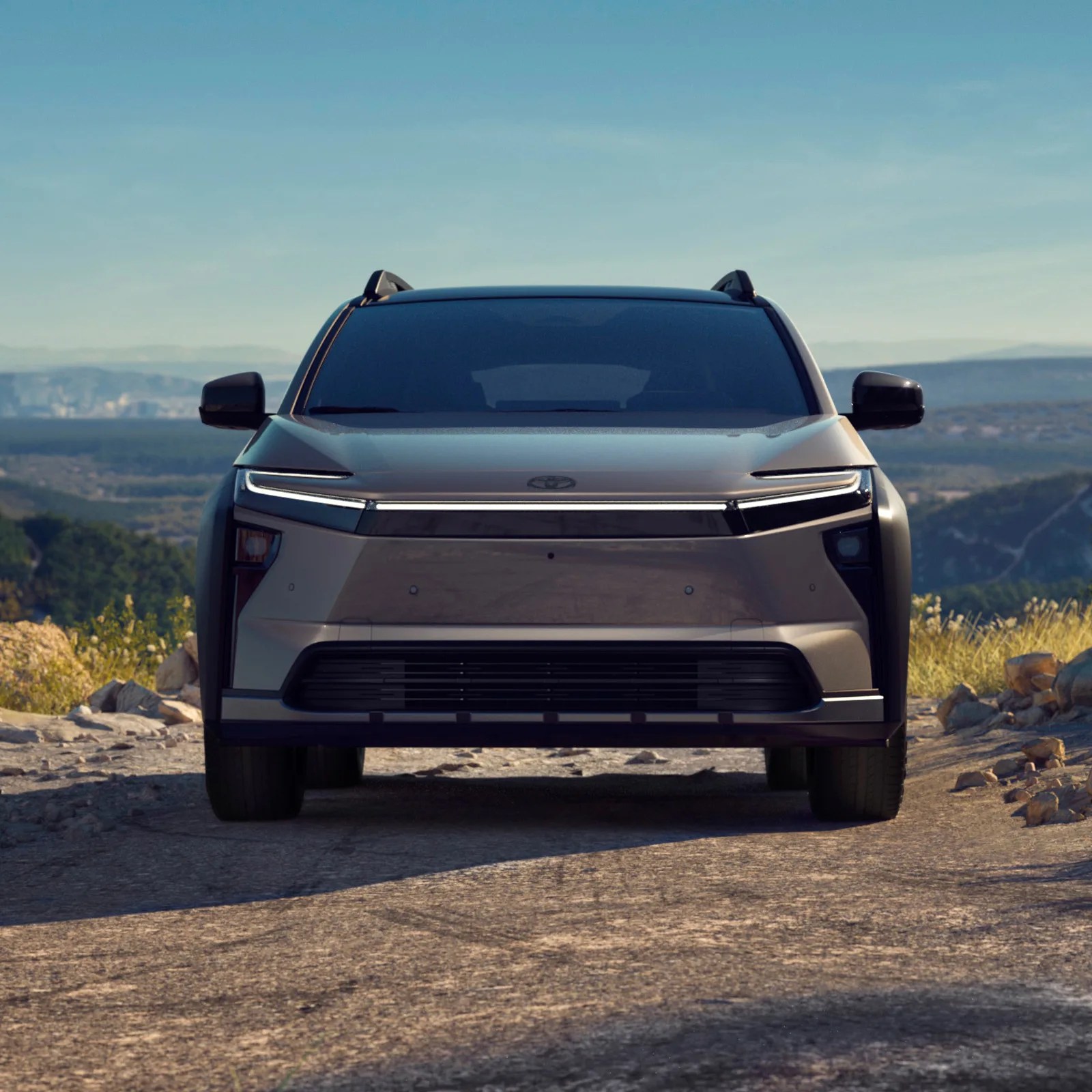 The Toyota bZ Woodland EV parked and shown facing head-on. The vehicle appears perched on a ridge with a valley behind it in the background. 
