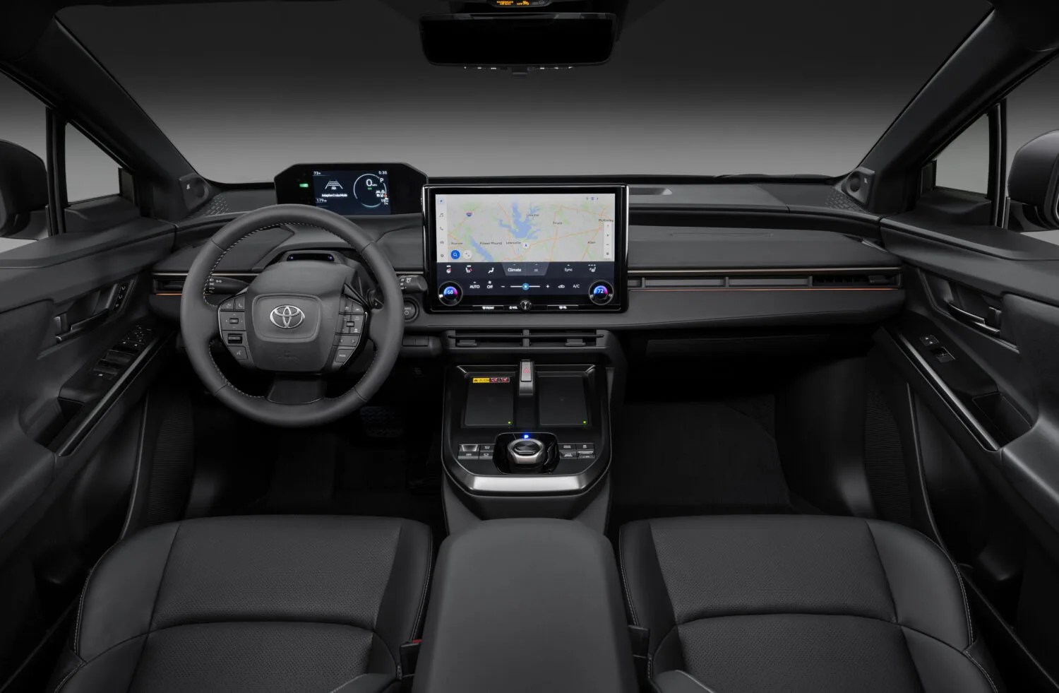 An interior view of the Toyota bZ Woodland EV showing the steering wheel dash and center infotainment screen. 
