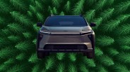 The front of the Toyota bZ Woodland EV shown head-on against an illustrated background of pin tree tops
