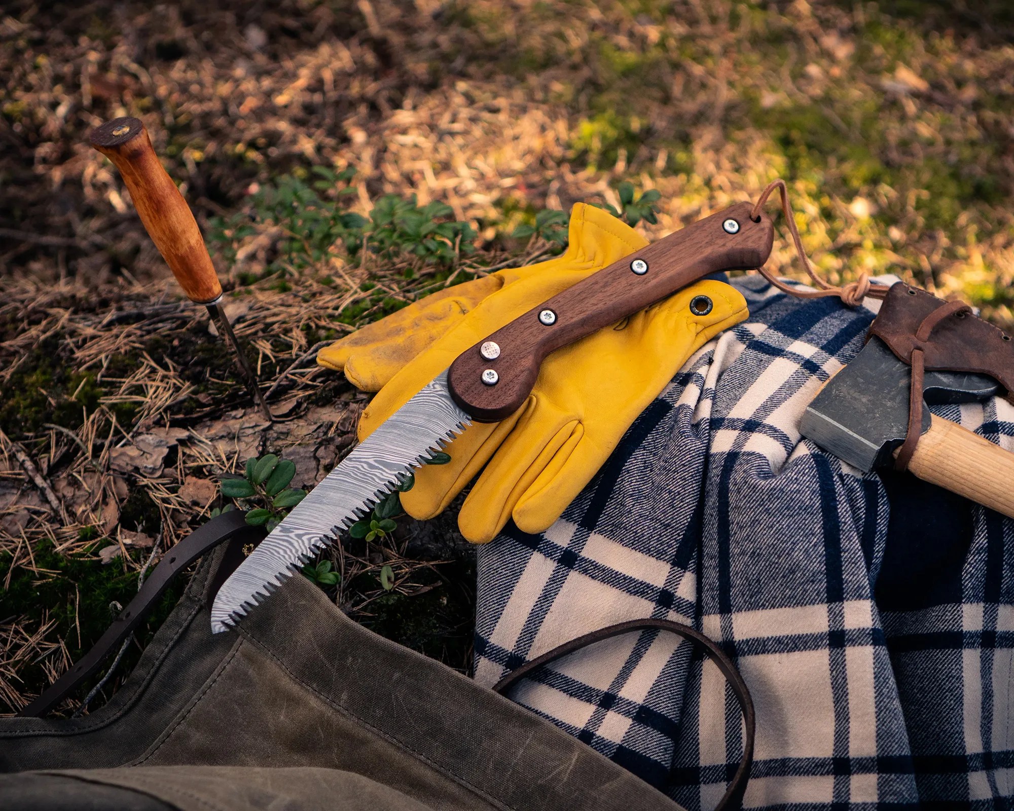 Woxna Damascus Steel Folding Saw on gloves, shirt, bag and log