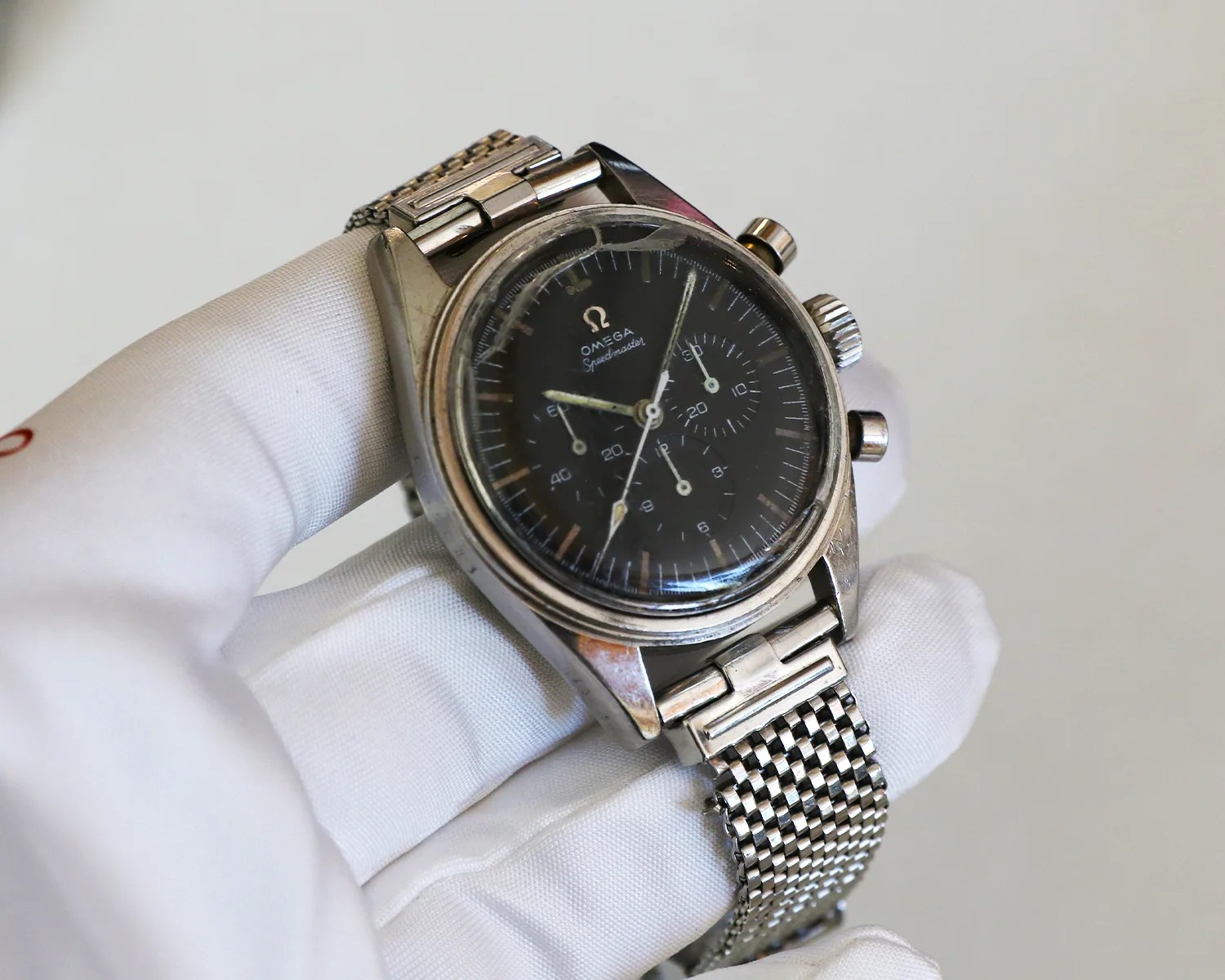 a gloved hand holds a vintage omega speedmaster watch that was worn on the moon