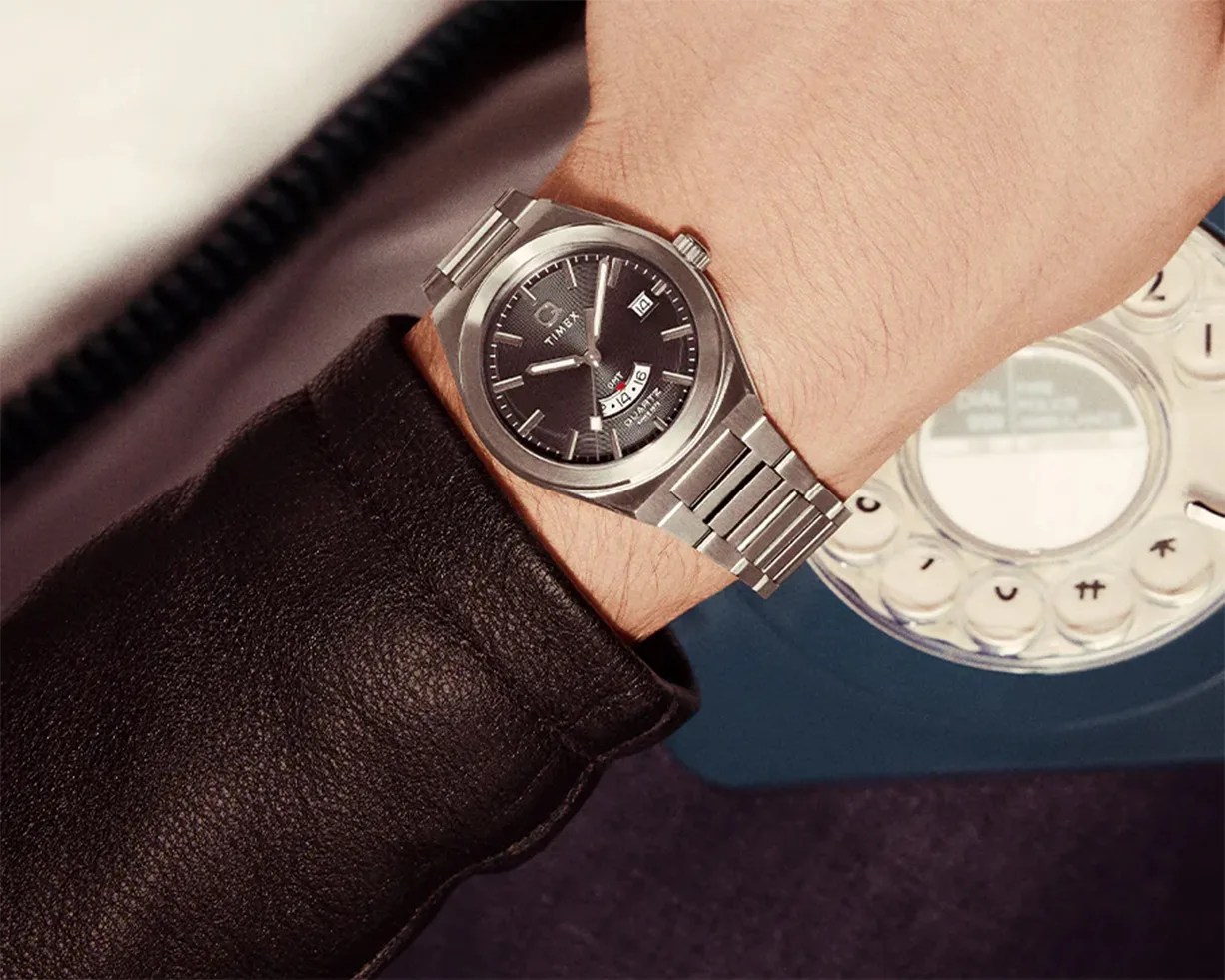 a steel Q Timex watch on a man's wrist