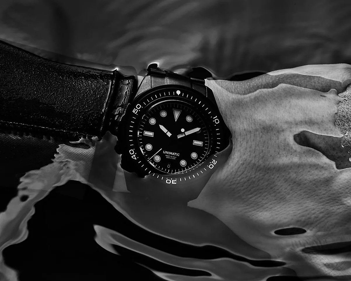 a black Unimatic dive watch on a diver's wrist
