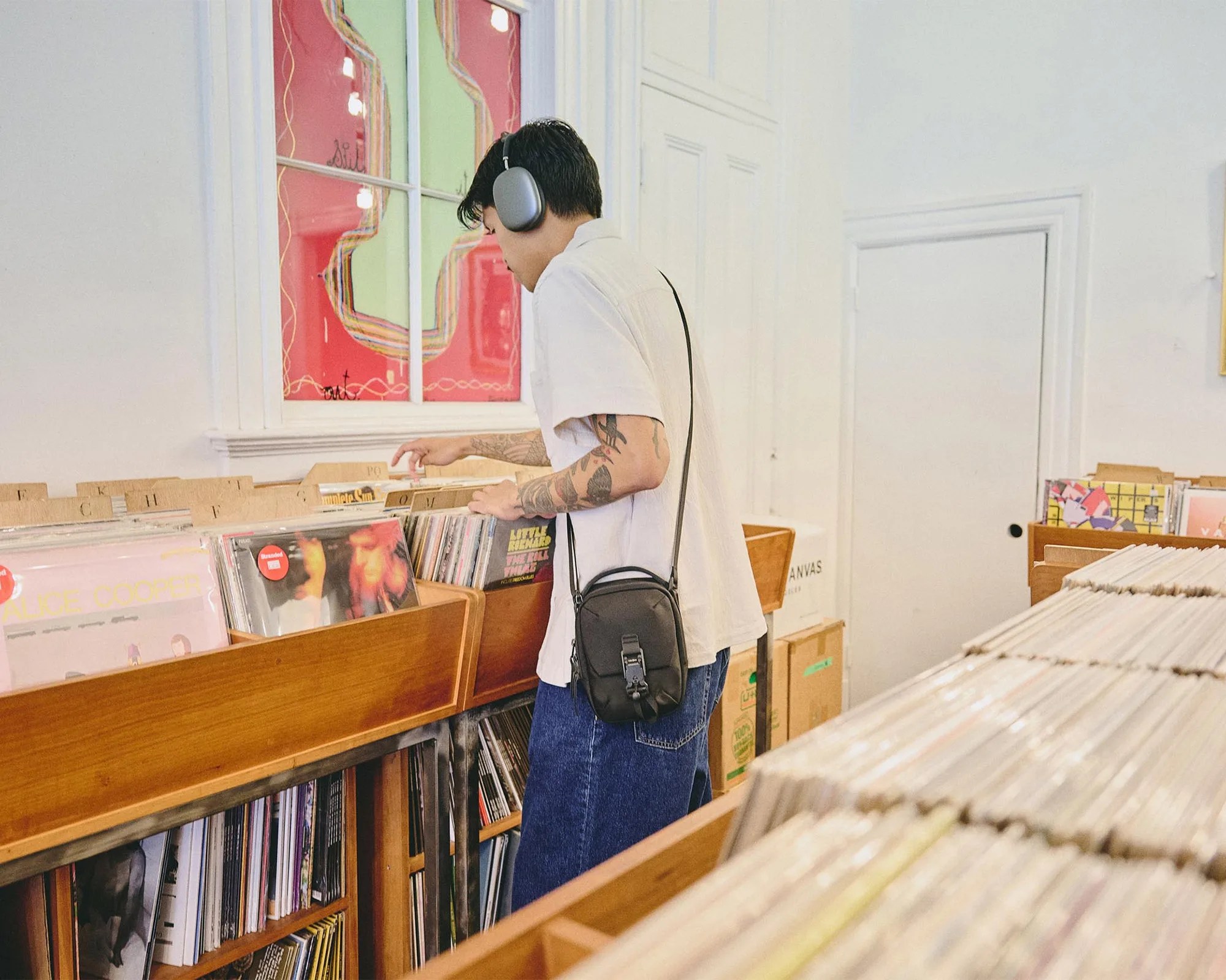 Aer Street Sling EDC Crossbody Pack worn by person in headphones in record store