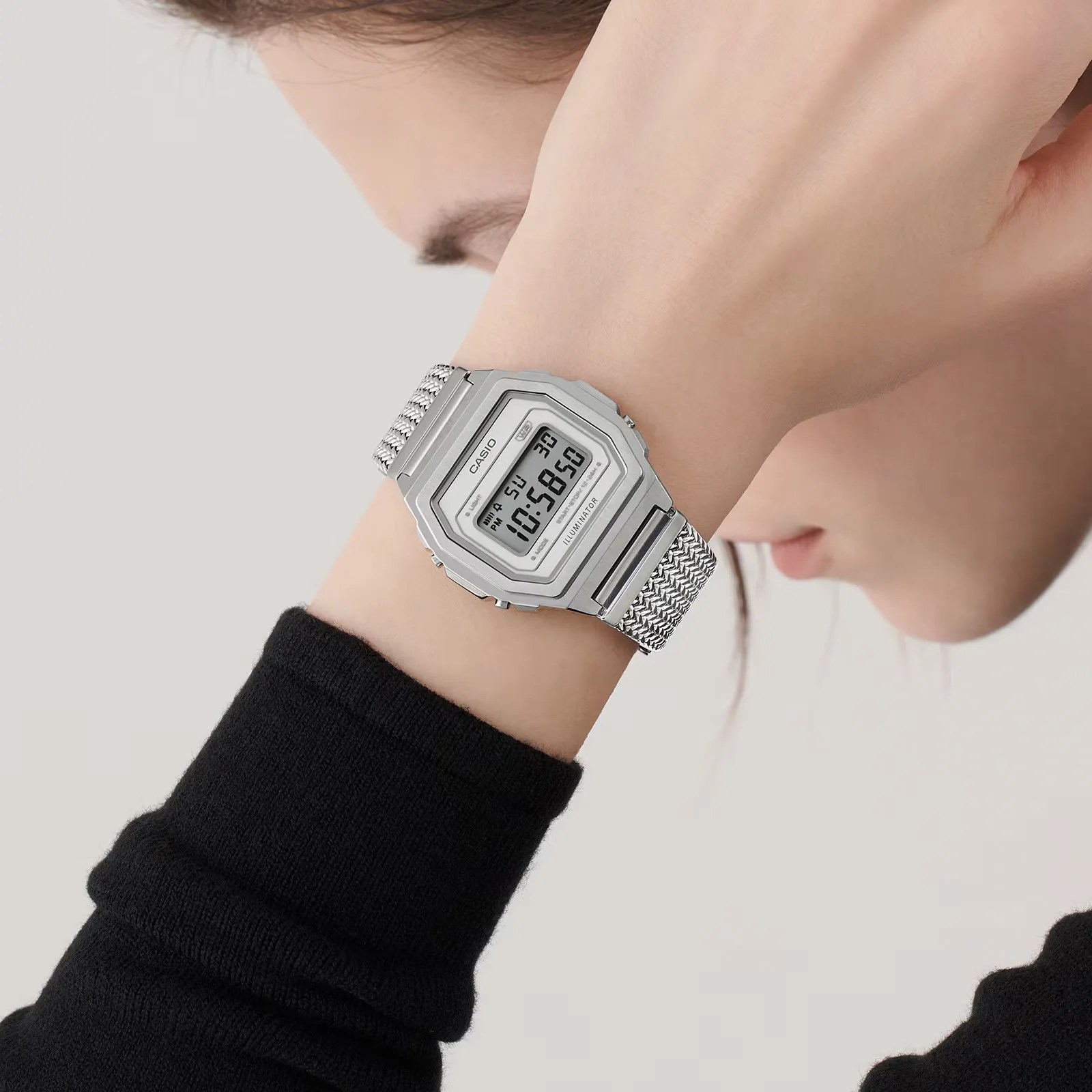 A women wearing a Casio A1000MA-7VT watch on her wrist holding her arm up with her hand concealing most of her face shown in a profile view