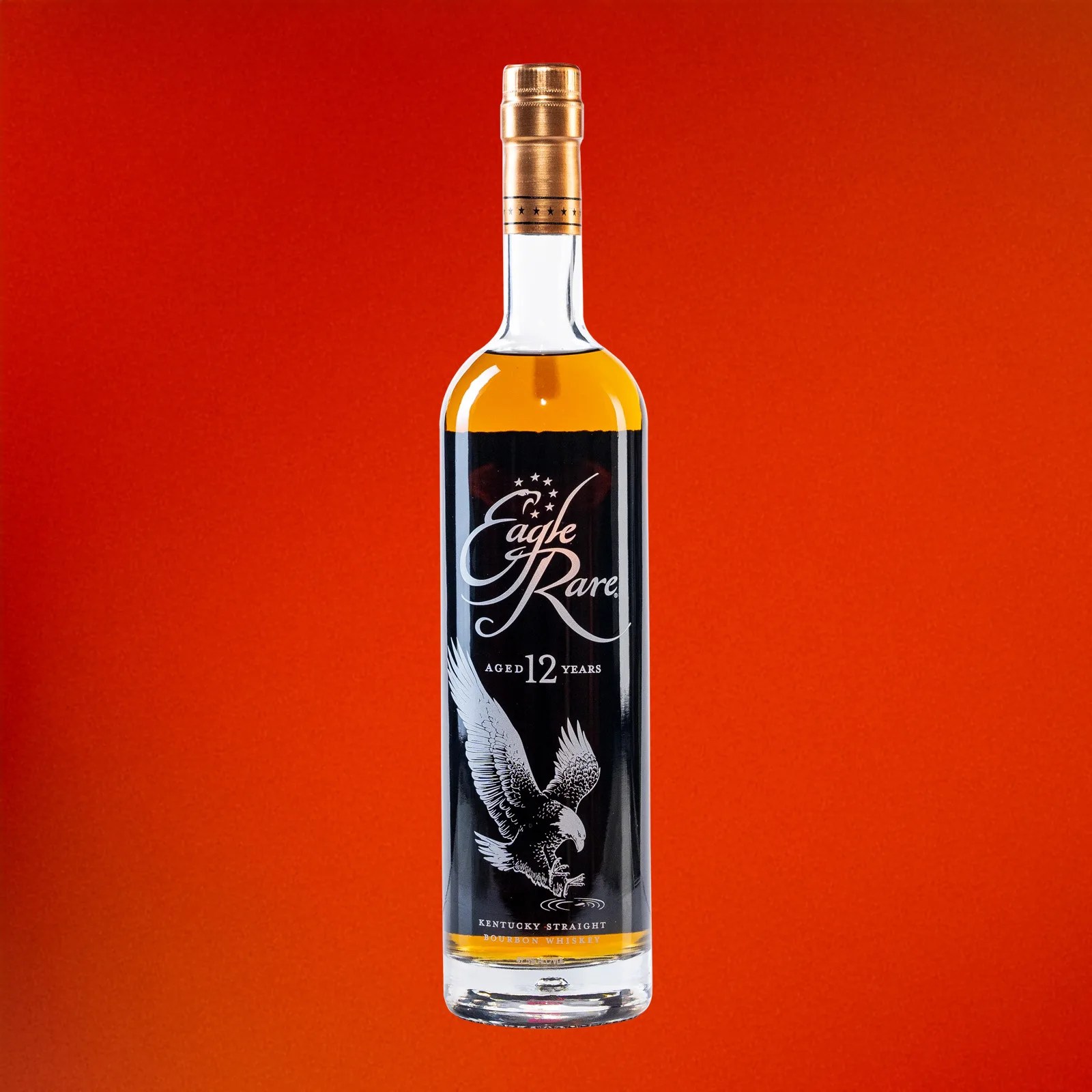 A bottle of Eagle Rare 12 Bourbon against a reddish-orange background