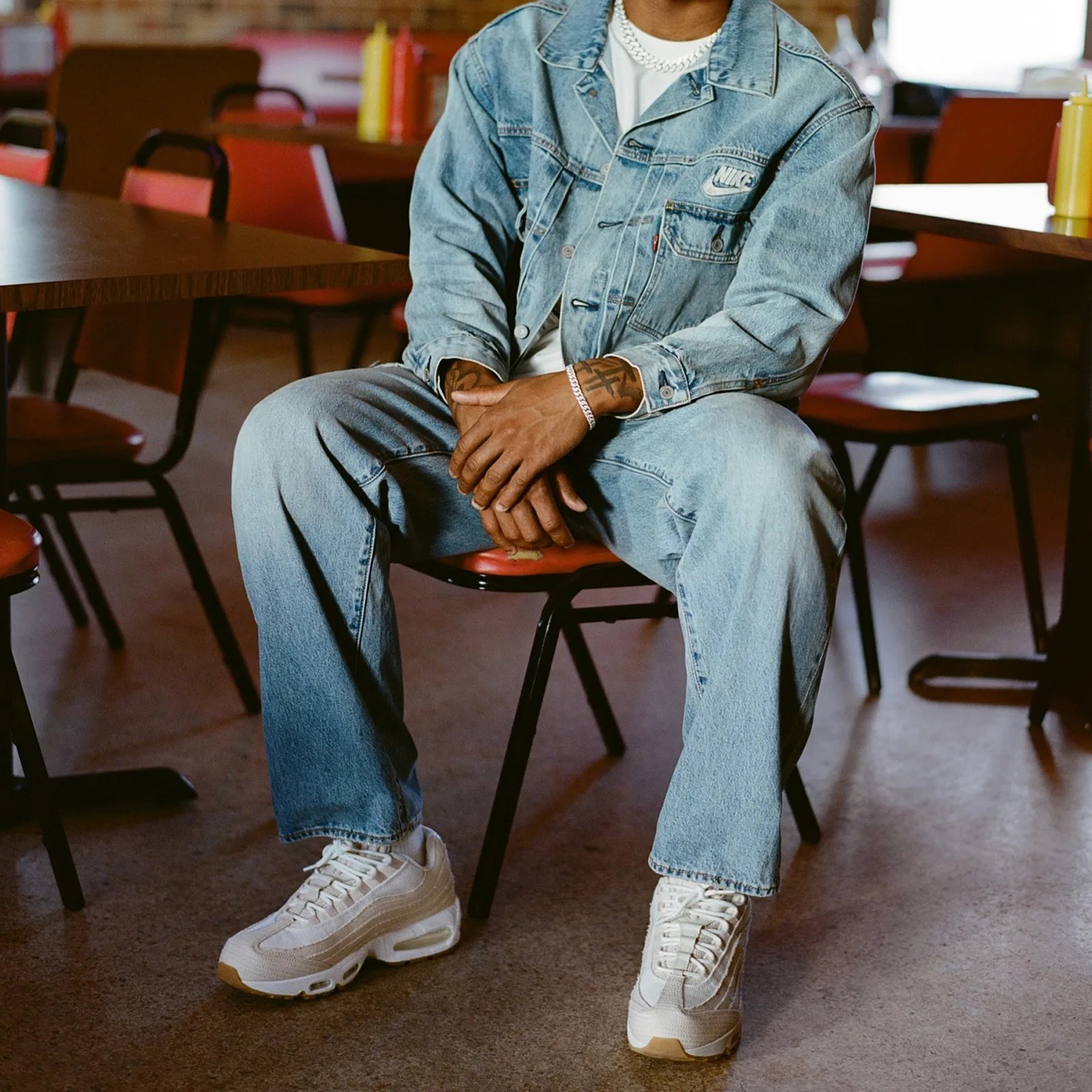 A man wearing a set of Nike x Levi's jeans and a denim jacket wearing a pair of white Nike x Levi's Air Max 95 sneakers
