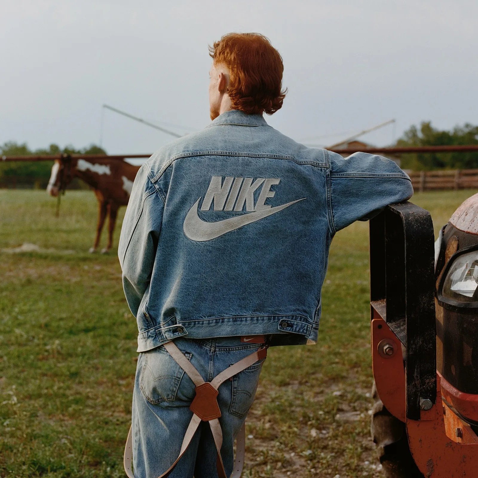 A man wearing a Nike branded Levi's denim trucker jacket that shows the Nike and Swoosh logo on the back