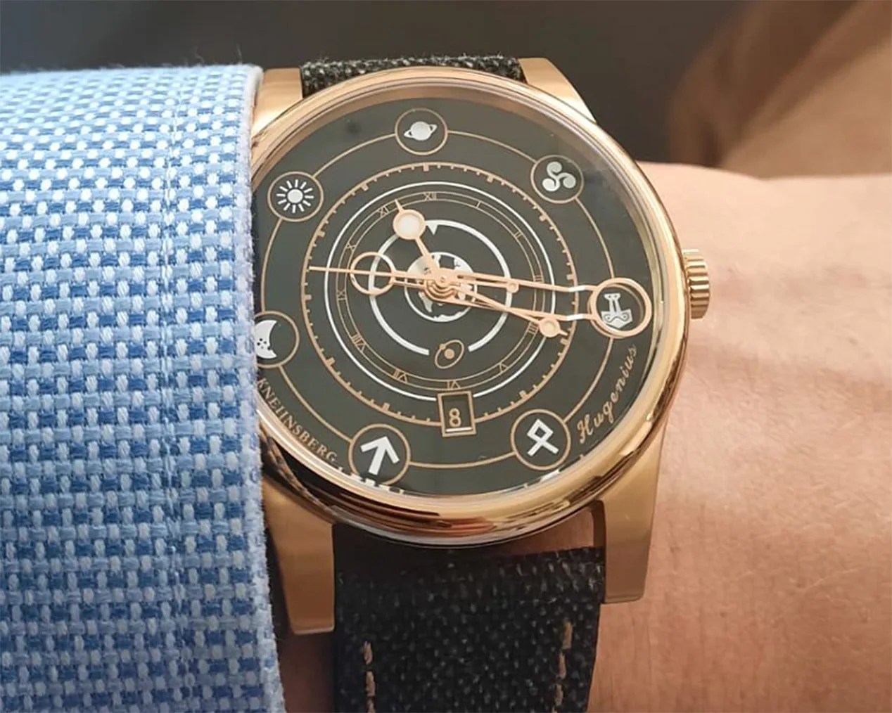 A gold Kneijnsberg watch on a man's wrist