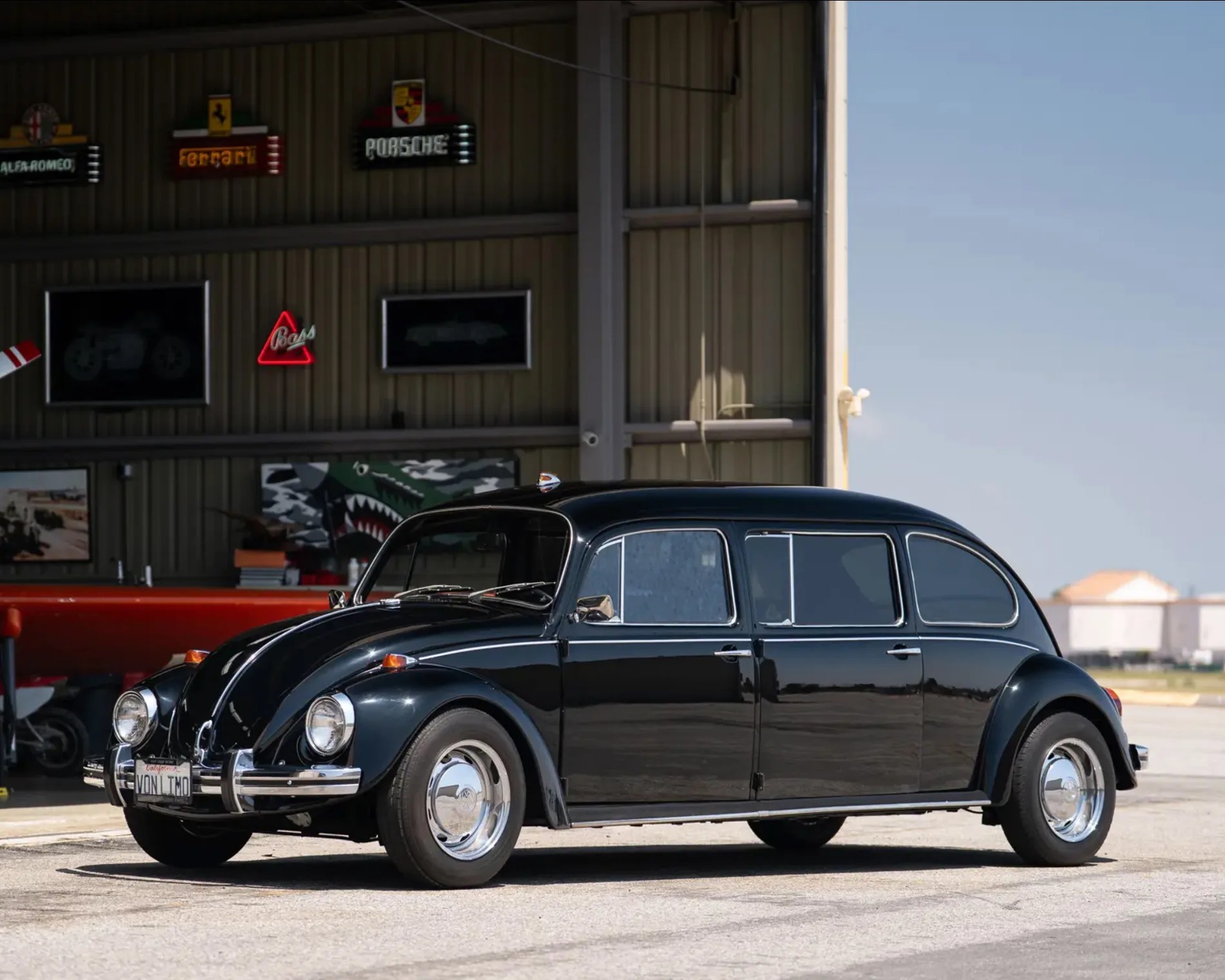 front 3/4 shot of vw beetle limo in black outside of hangar