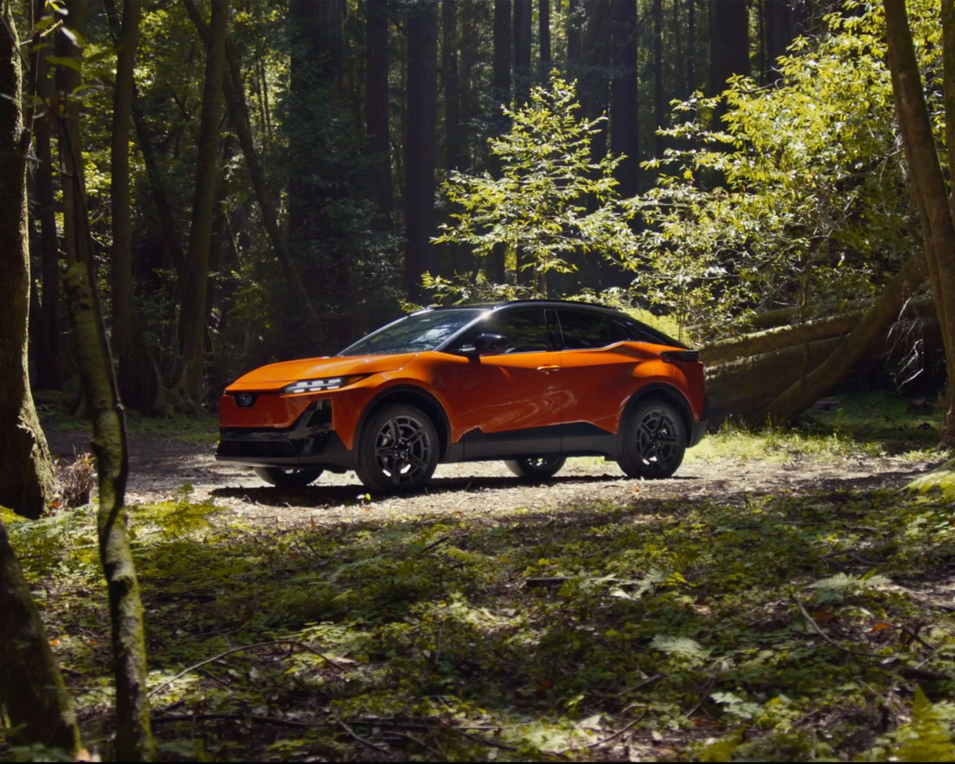orange electric subaru crossover parked wooded scene