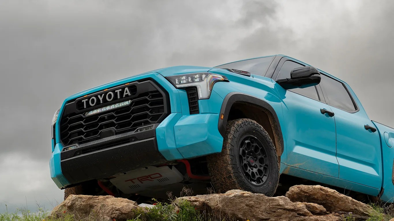 blue toyota pickup perched on rocky ledge