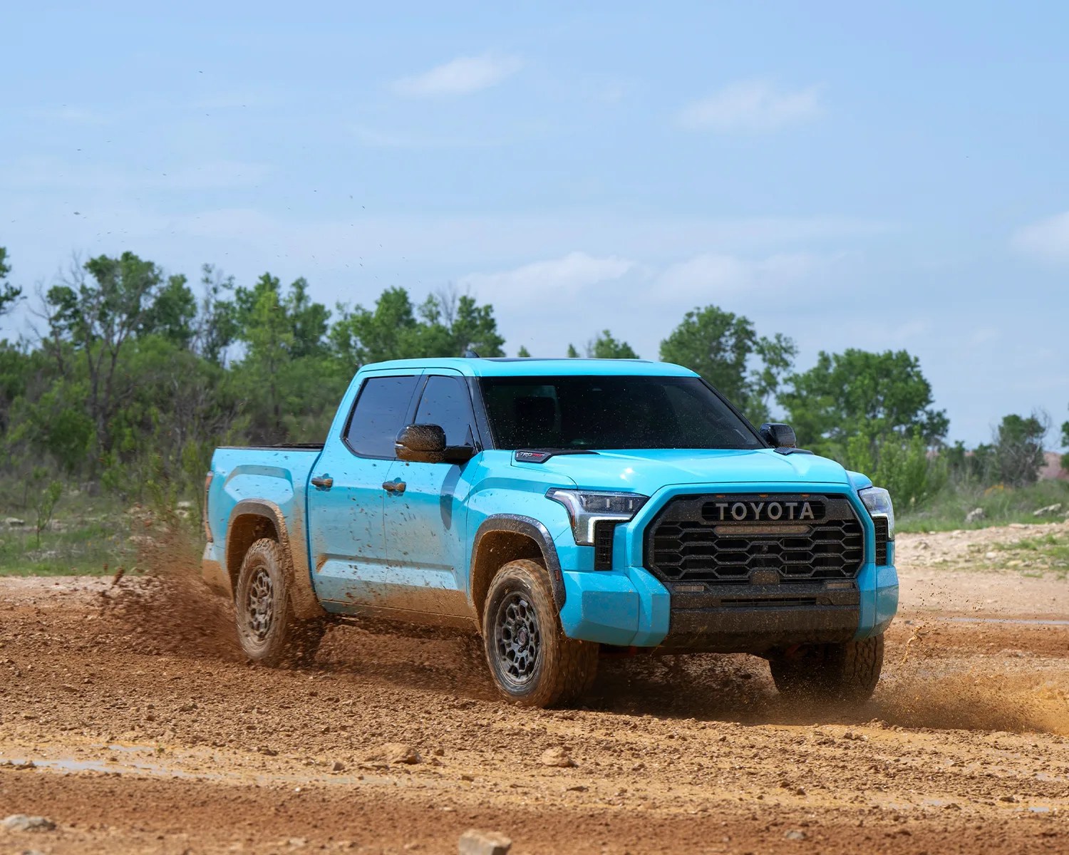 blue toyota tundra truck driving through dirt