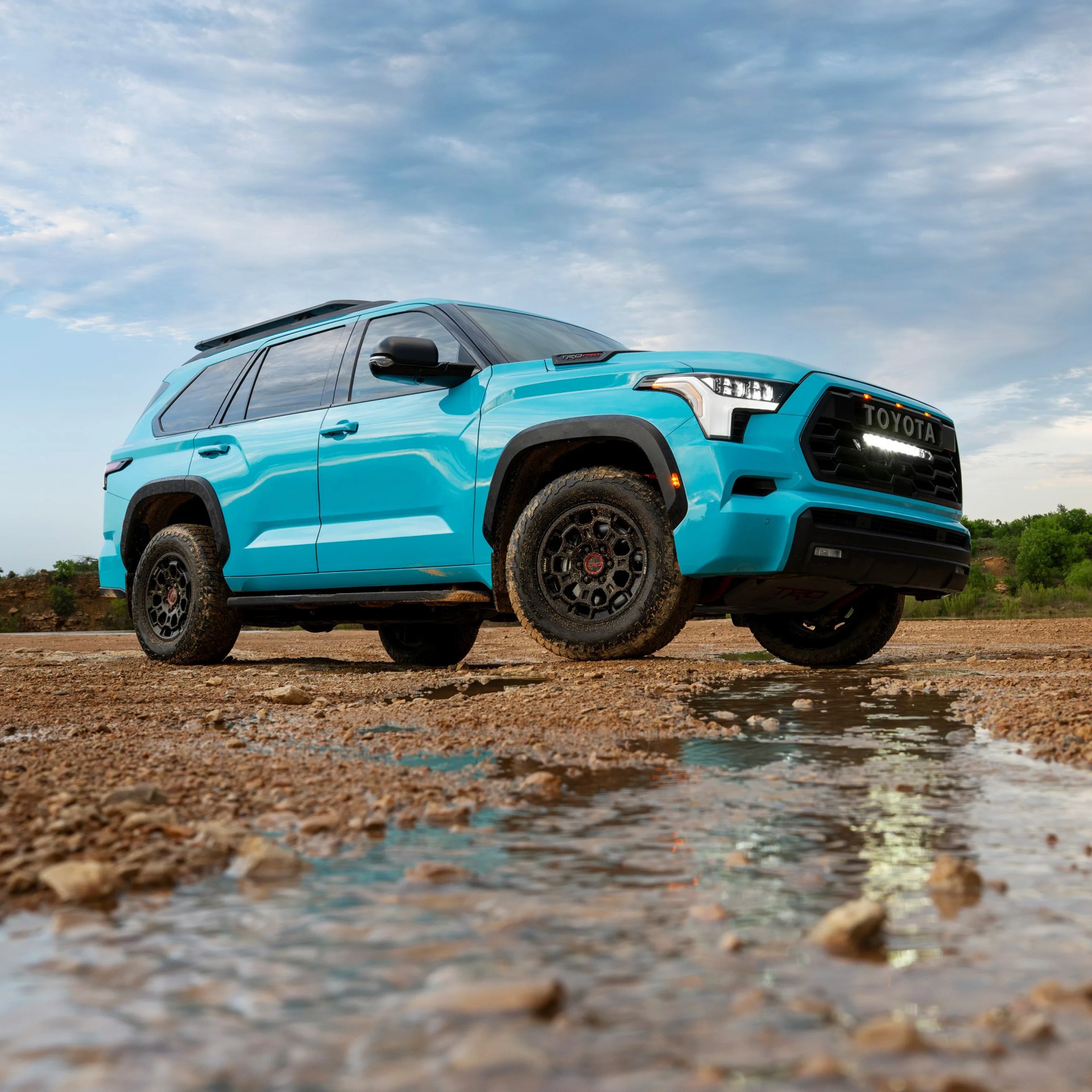 low perspective shot of a toyota SUV parked on gravel with puddle