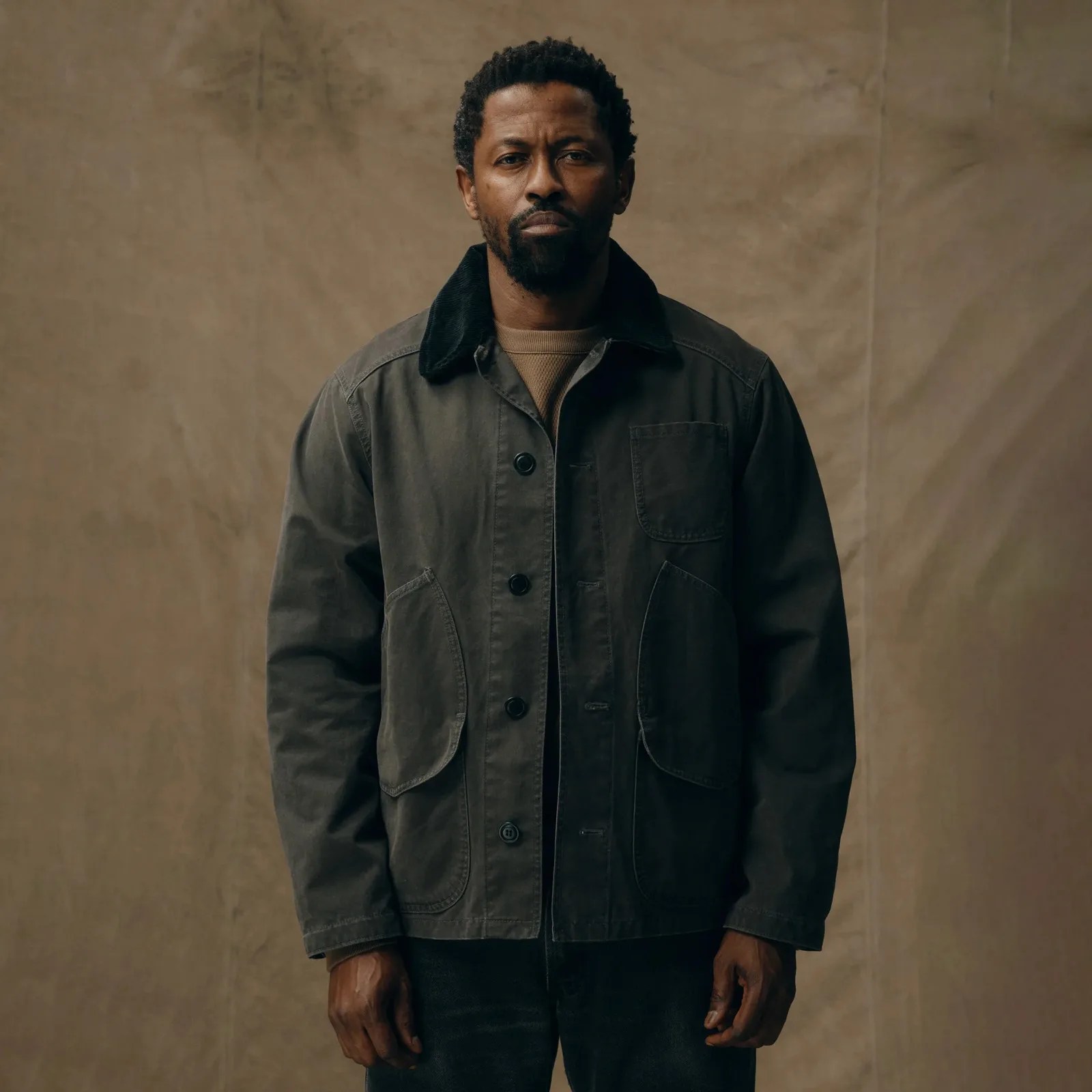 A man wearing the Filson Canvas Outfitter Jacket with his hands at his side