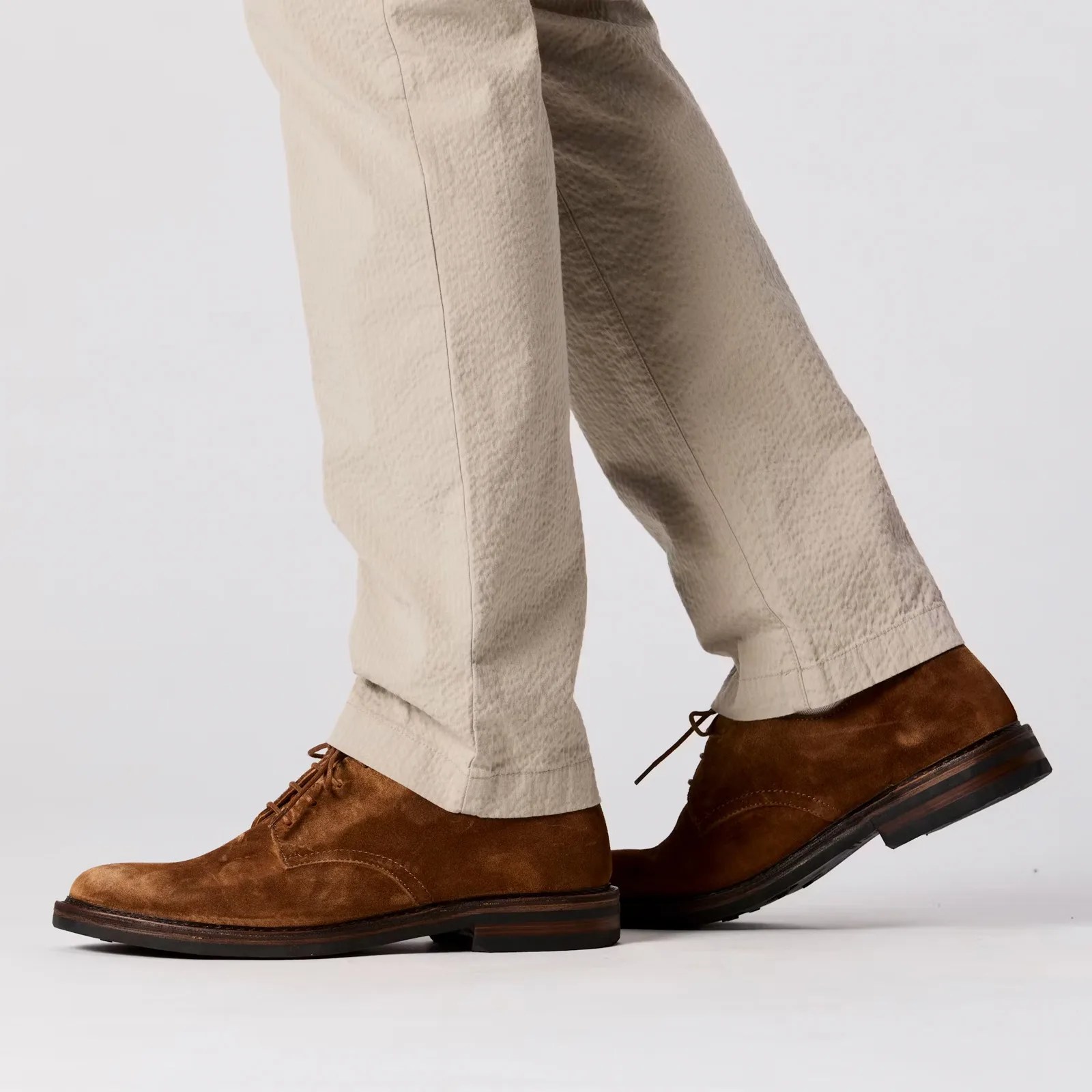 A close up of the cuffs of The Flint and Tinder Seersucker Trousers in Khaki being worn on a model wearing brown shoes
