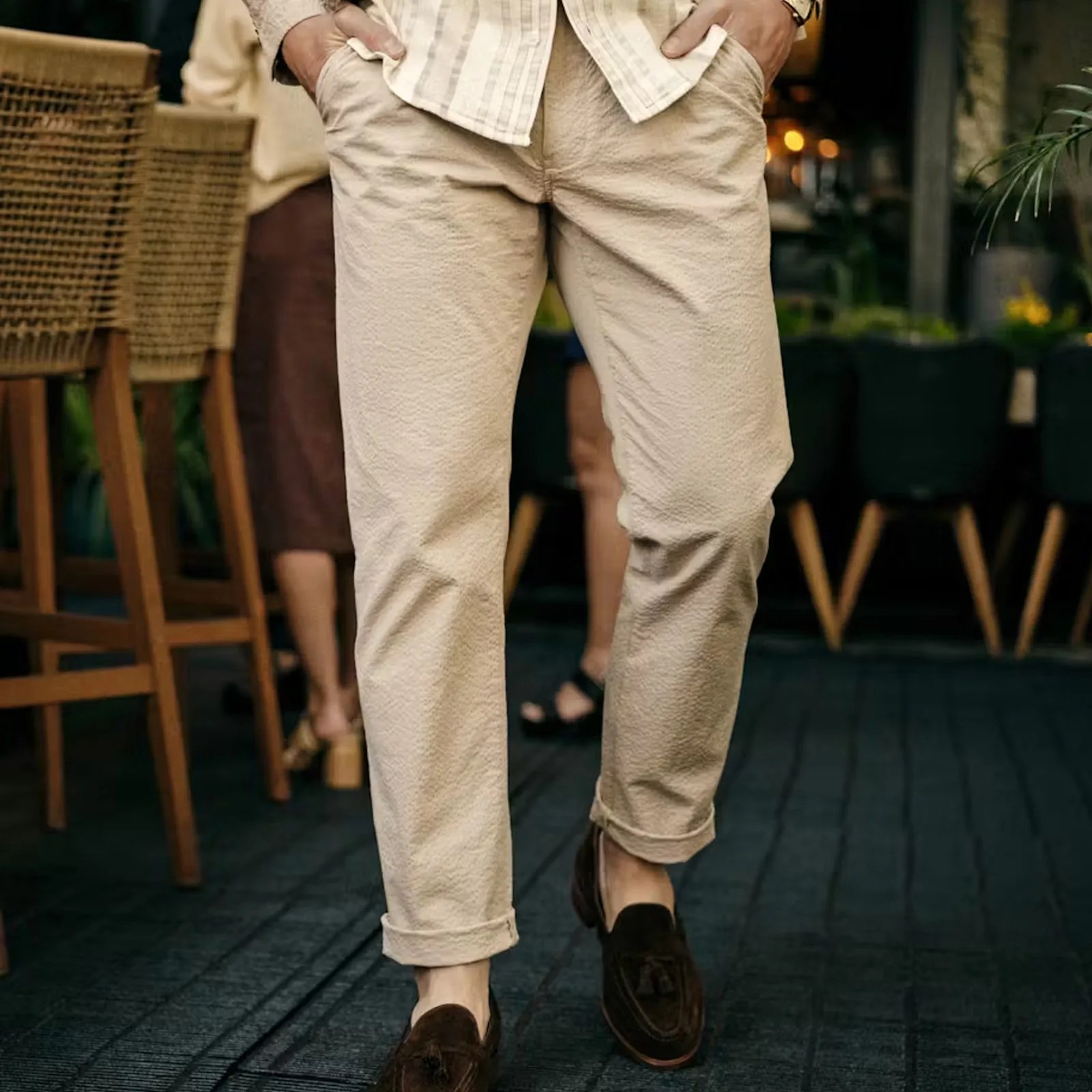 A male model wearing the Flint and Tinder Seersucker Trousers in Khaki shown from the waist down walking out of a restaurant