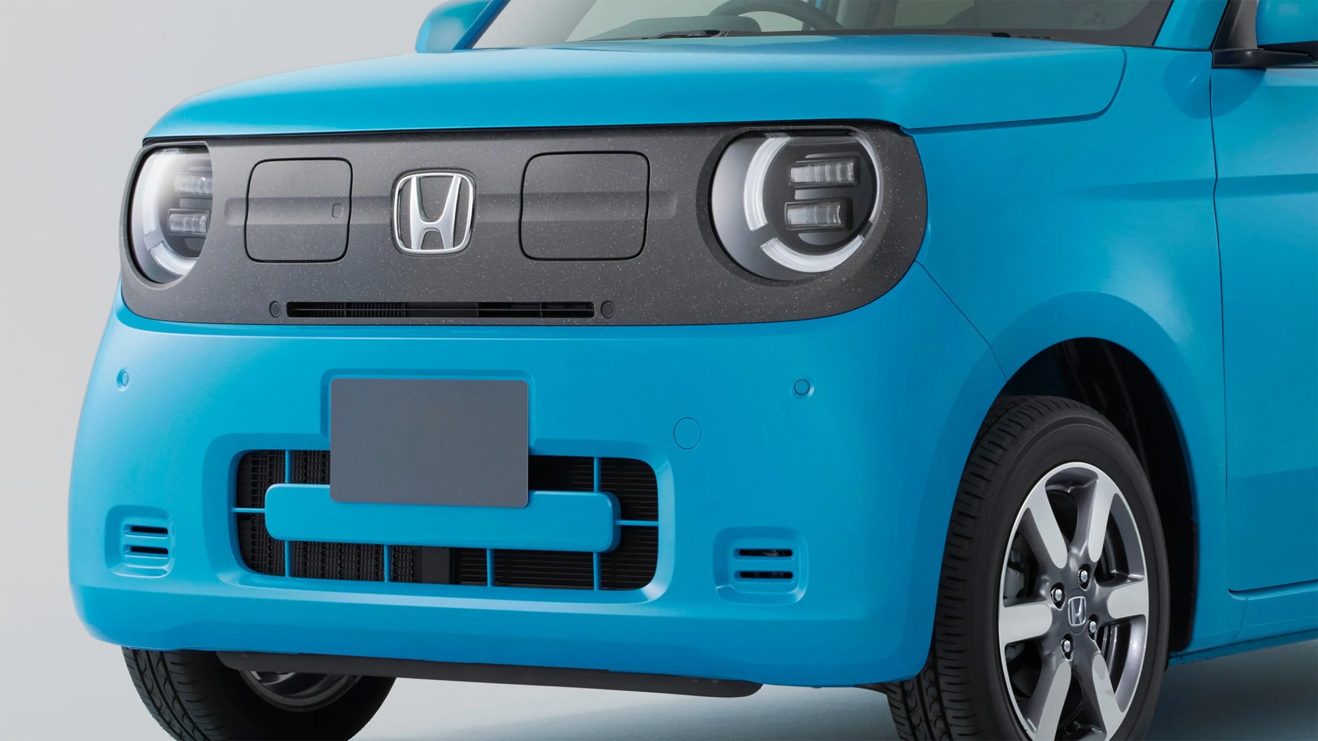 a close-up photo of the front grille of a blue honda compact