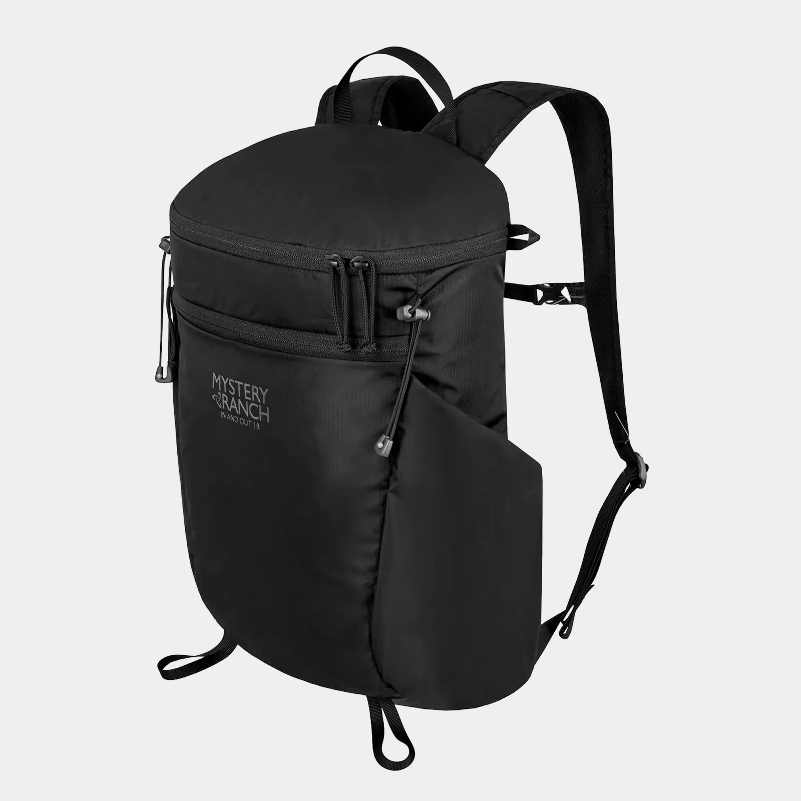 The Mystery Ranch In and Out 18L Backpack in black shown at an angle against a light grey background