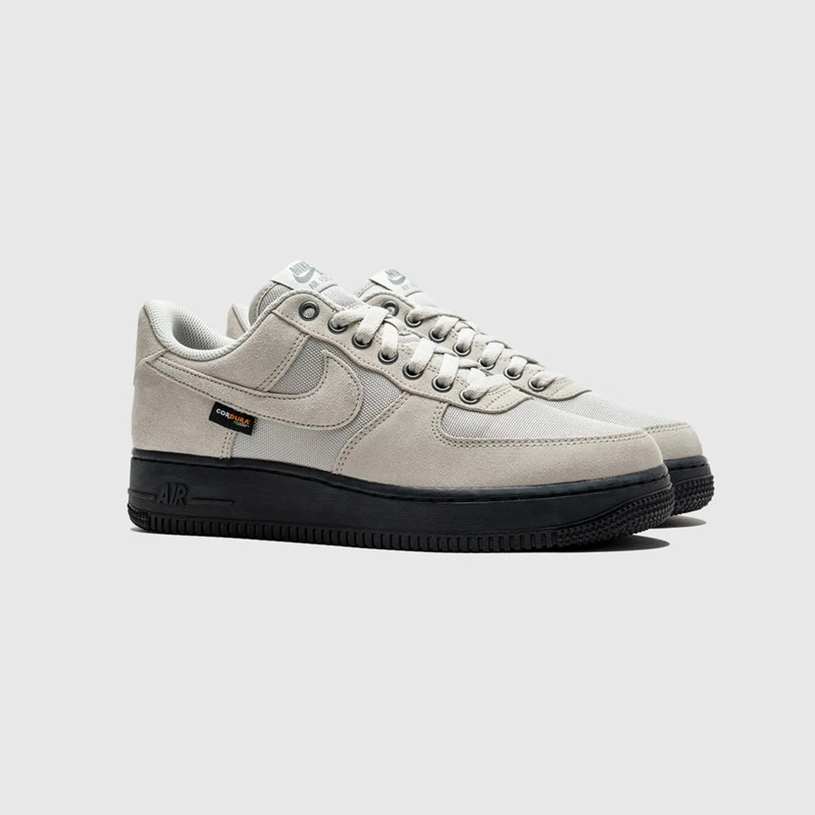 A pair of Nike Air Force 1 Cordura sneakers in light "Iron/Ore" gray with the shoe's toes pointed to the right is shown against a light grey background.