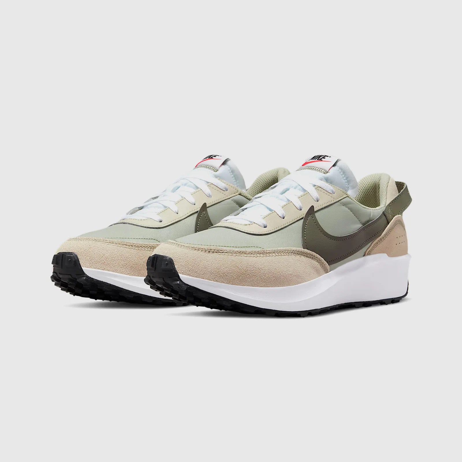 A pair of Nike Waffle Debut sneakers in light green and tan shown at an angle