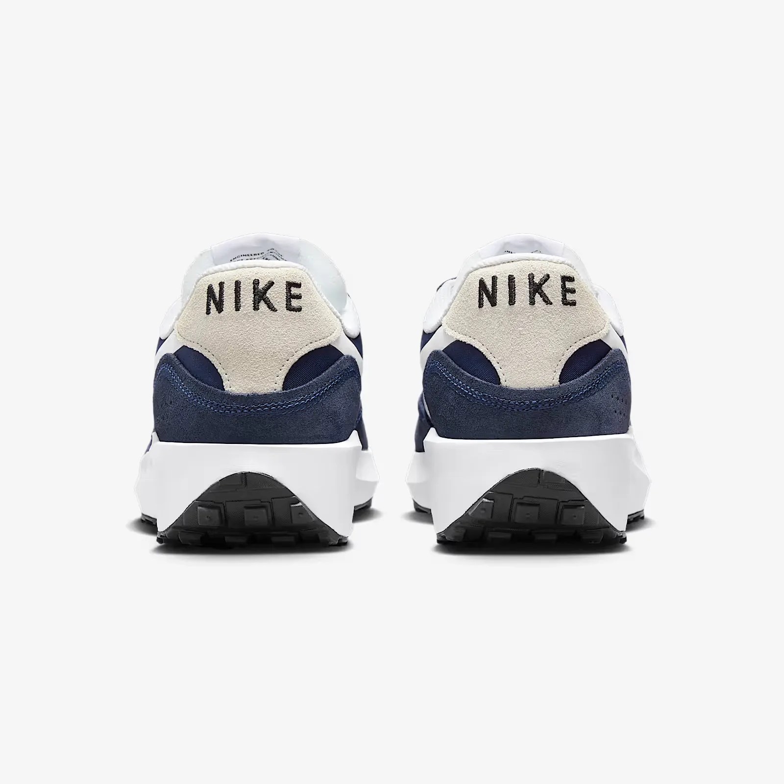 A pair of Nike Waffle Nav sneakers in midnight navy shown with the heels facing forward against a light grey background