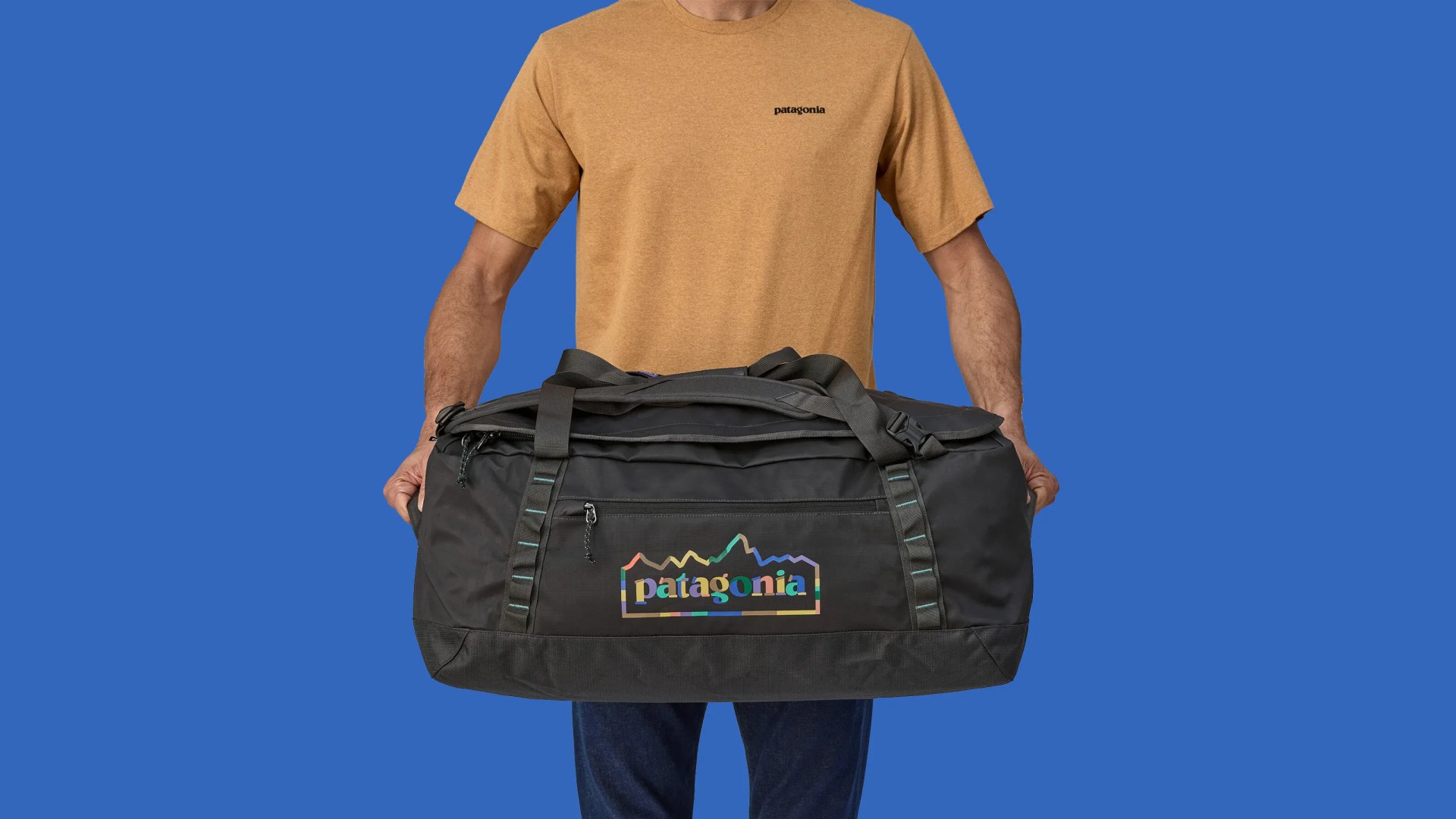 A man holding Patagonia Black Hole Duffel against a light blue background