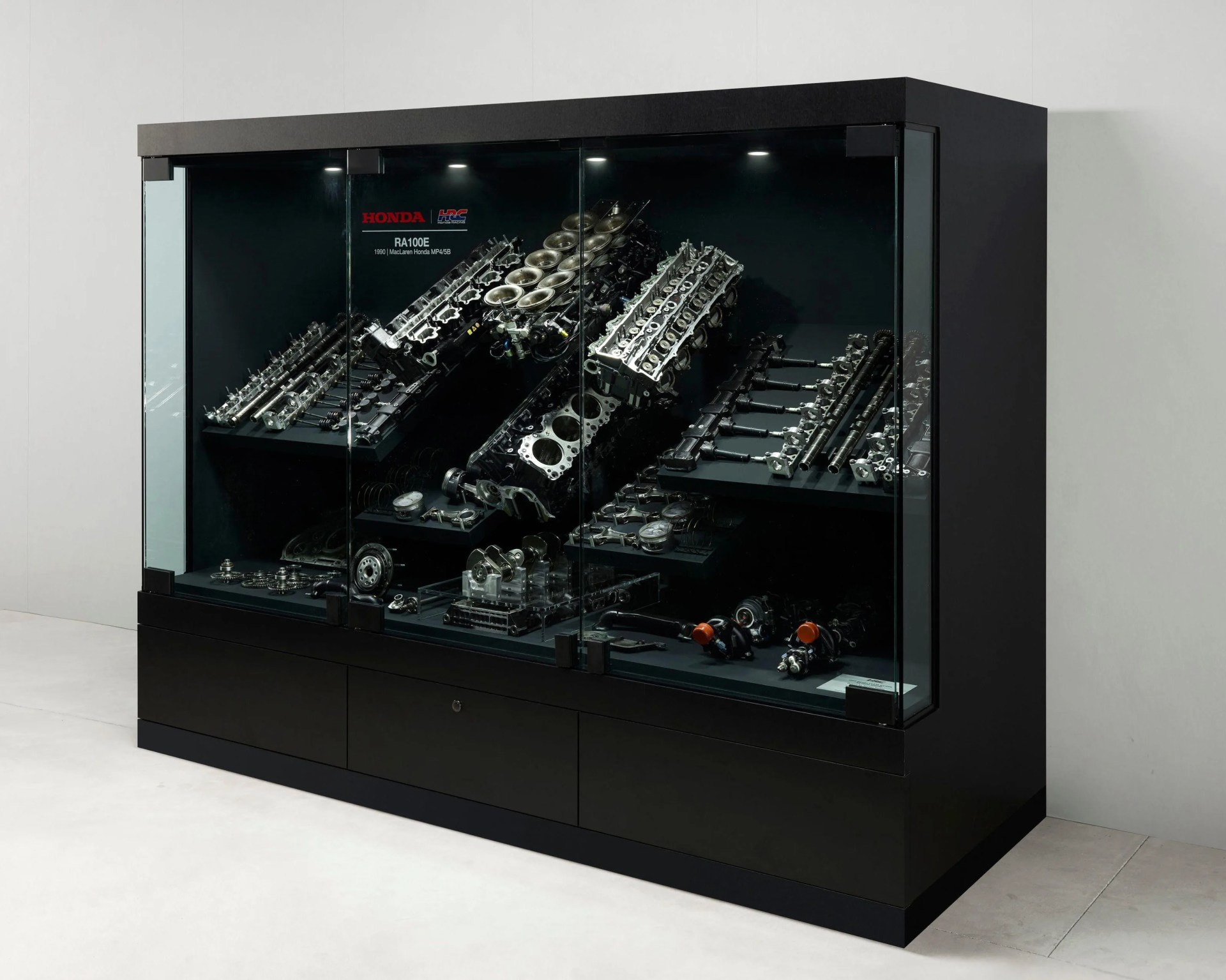 a side shot of a display case showing a disassembled honda formula one engine