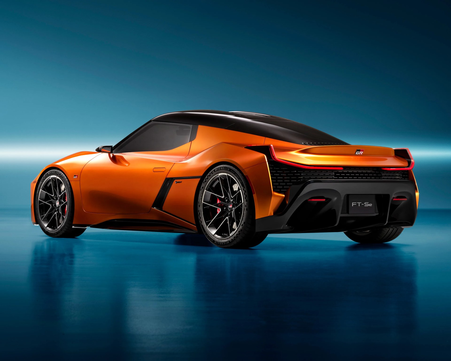 a photo showing the rear of an orange toyota concept in studio