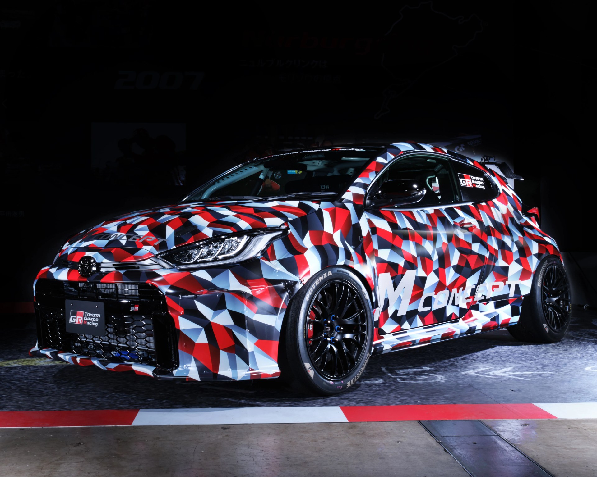 a 3/4 photo of a red, white and black camoflage toyota yaris prototype