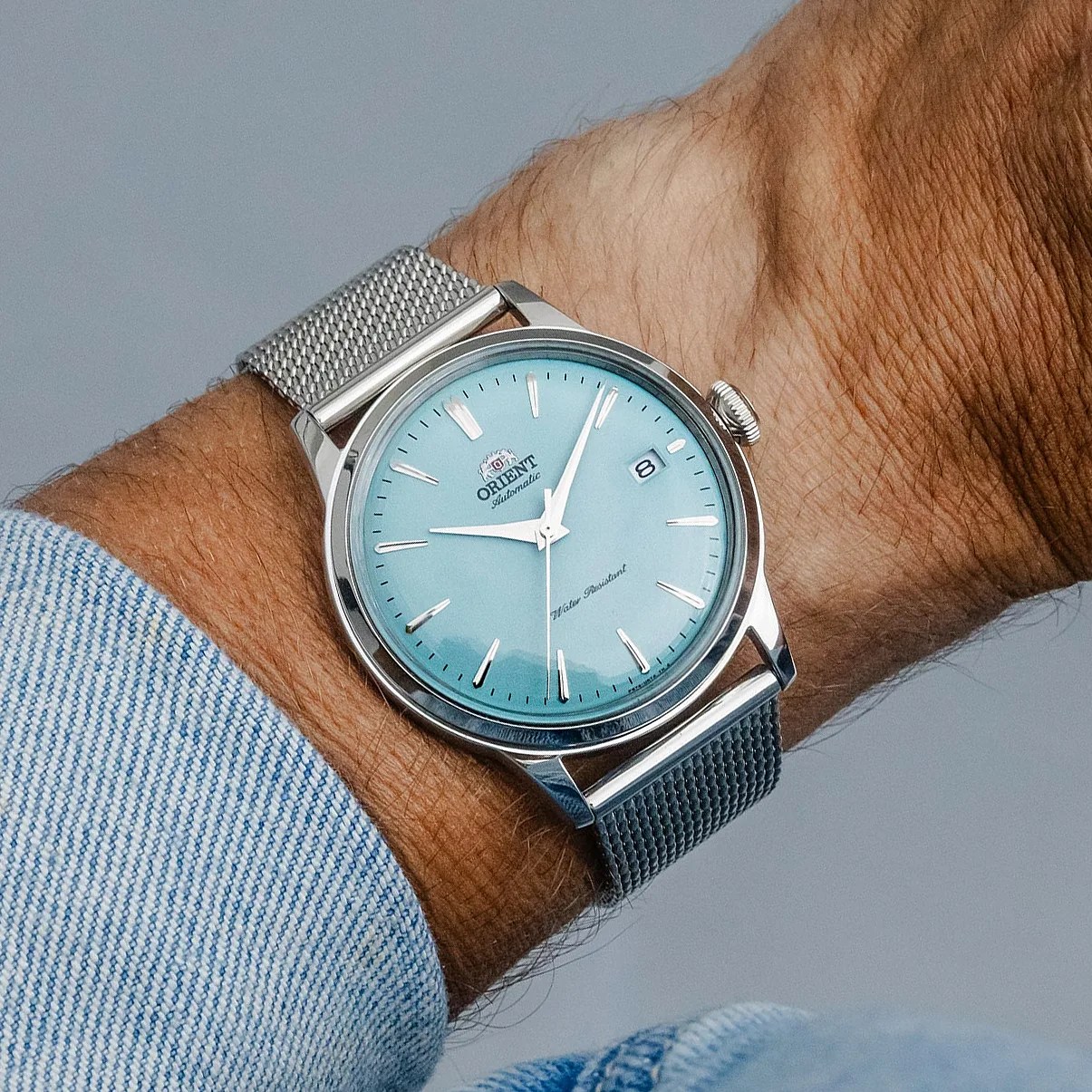 a baby blue orient watch on a man's wrist