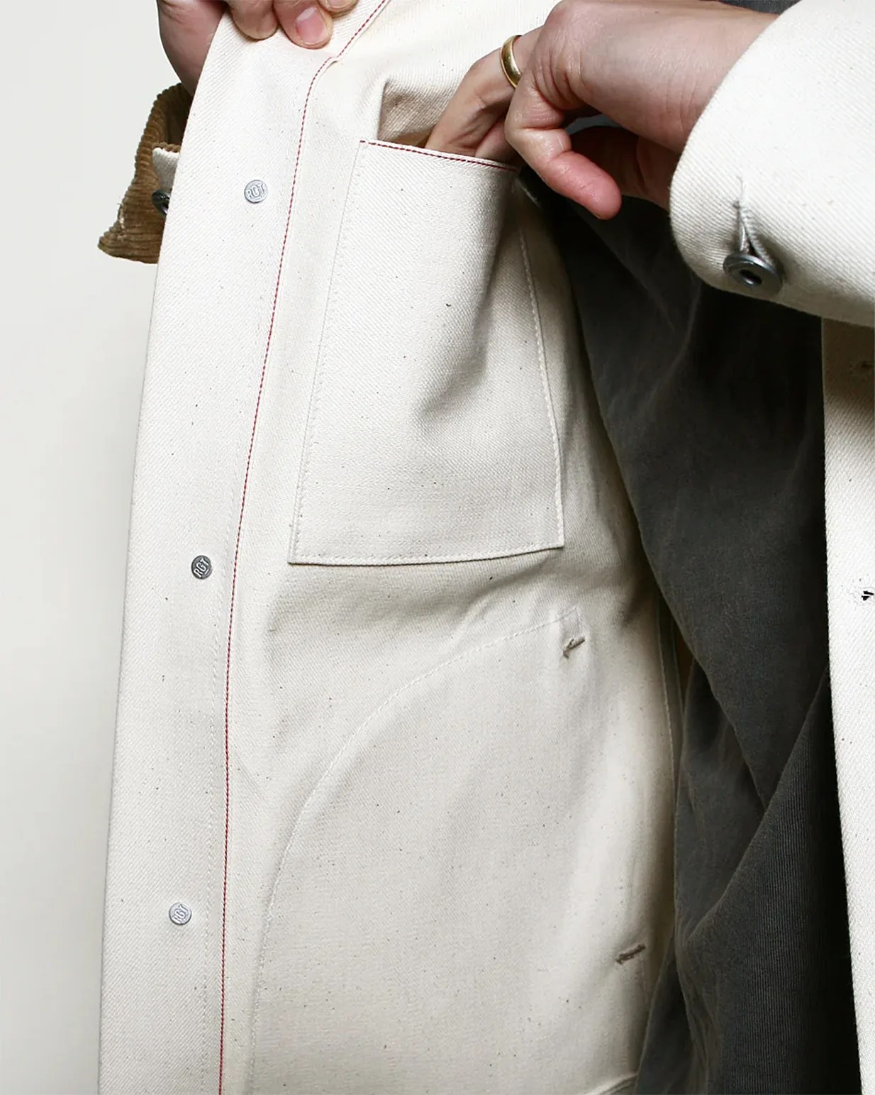 a man reaching into the pocket of a his white denim jacket