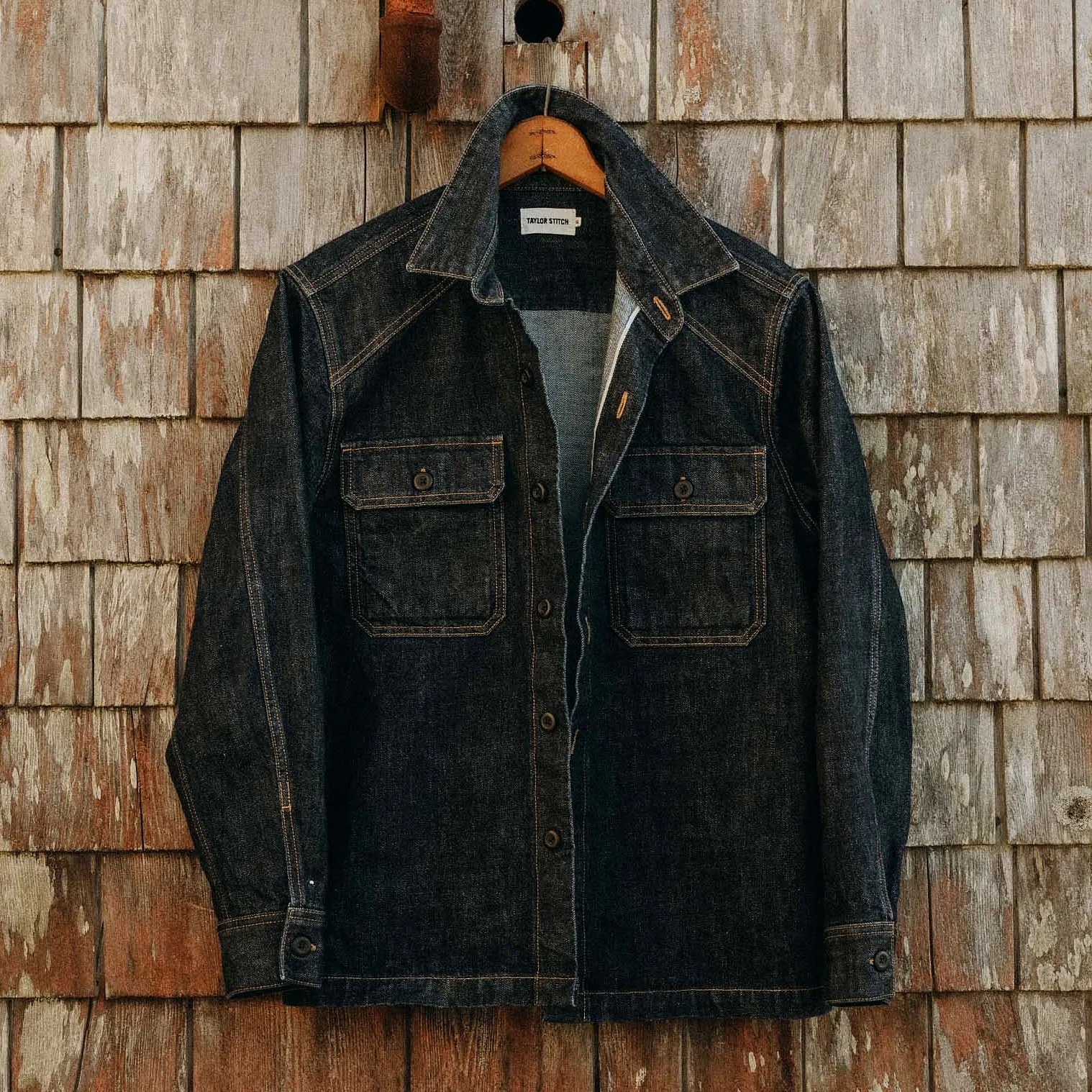 a denim work jacket hanging on a hanger