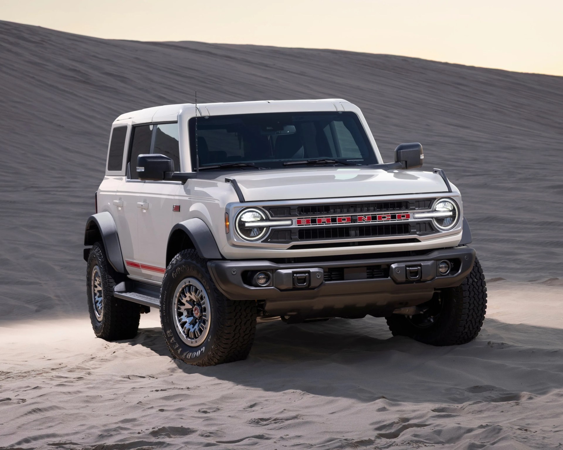 a front right 3/4 shot of a white ford bronco suv illuminated by overhead lighting
